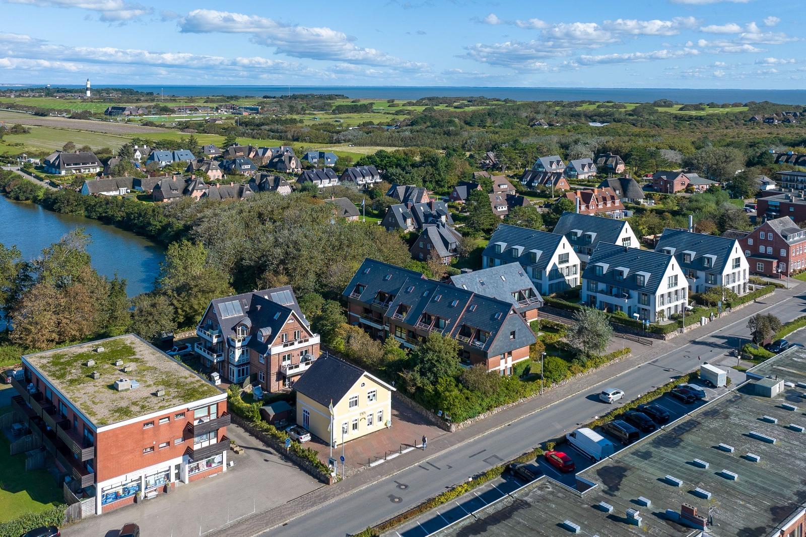 Village with houses, river, and sea in the background.