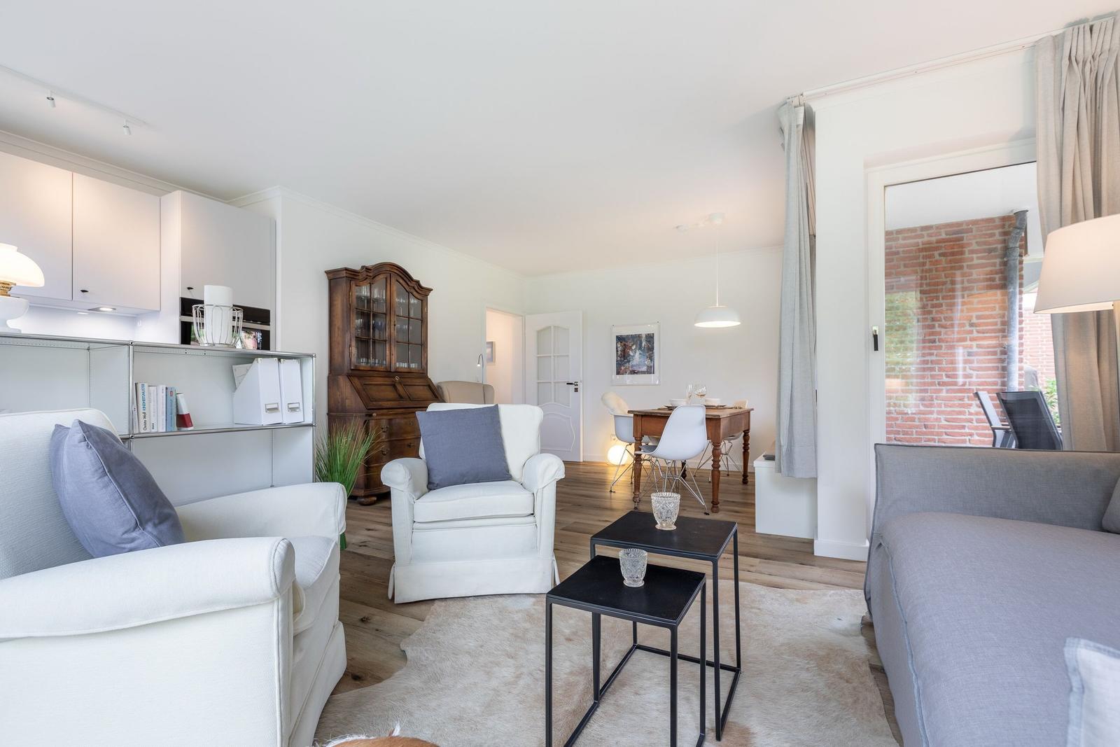 Living and dining area with sofa, armchairs, and wooden floor.