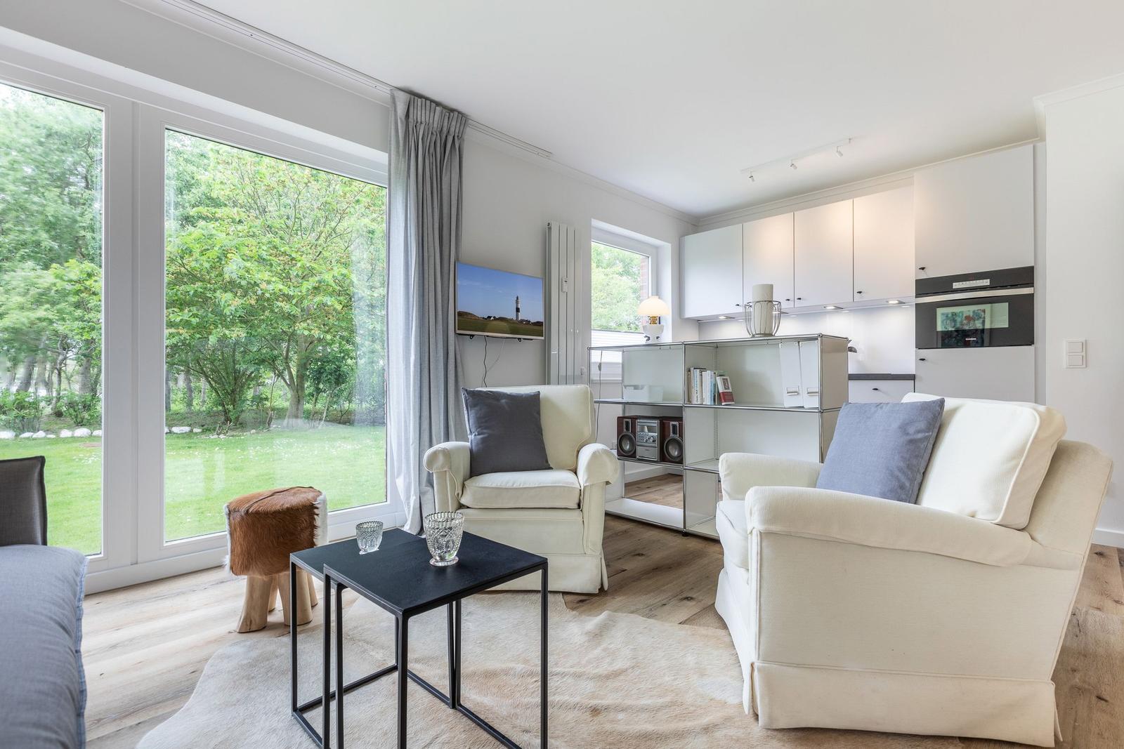 Living area with seating, kitchenette, and view of a garden.