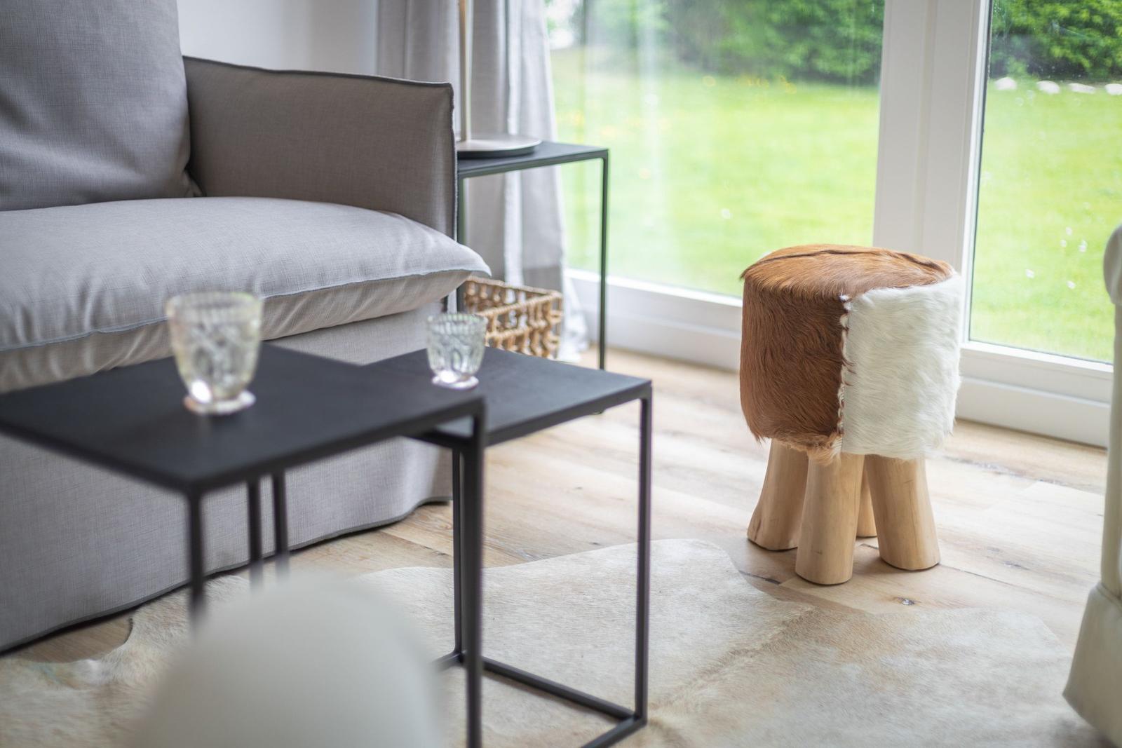 A gray sofa with table and stool by window