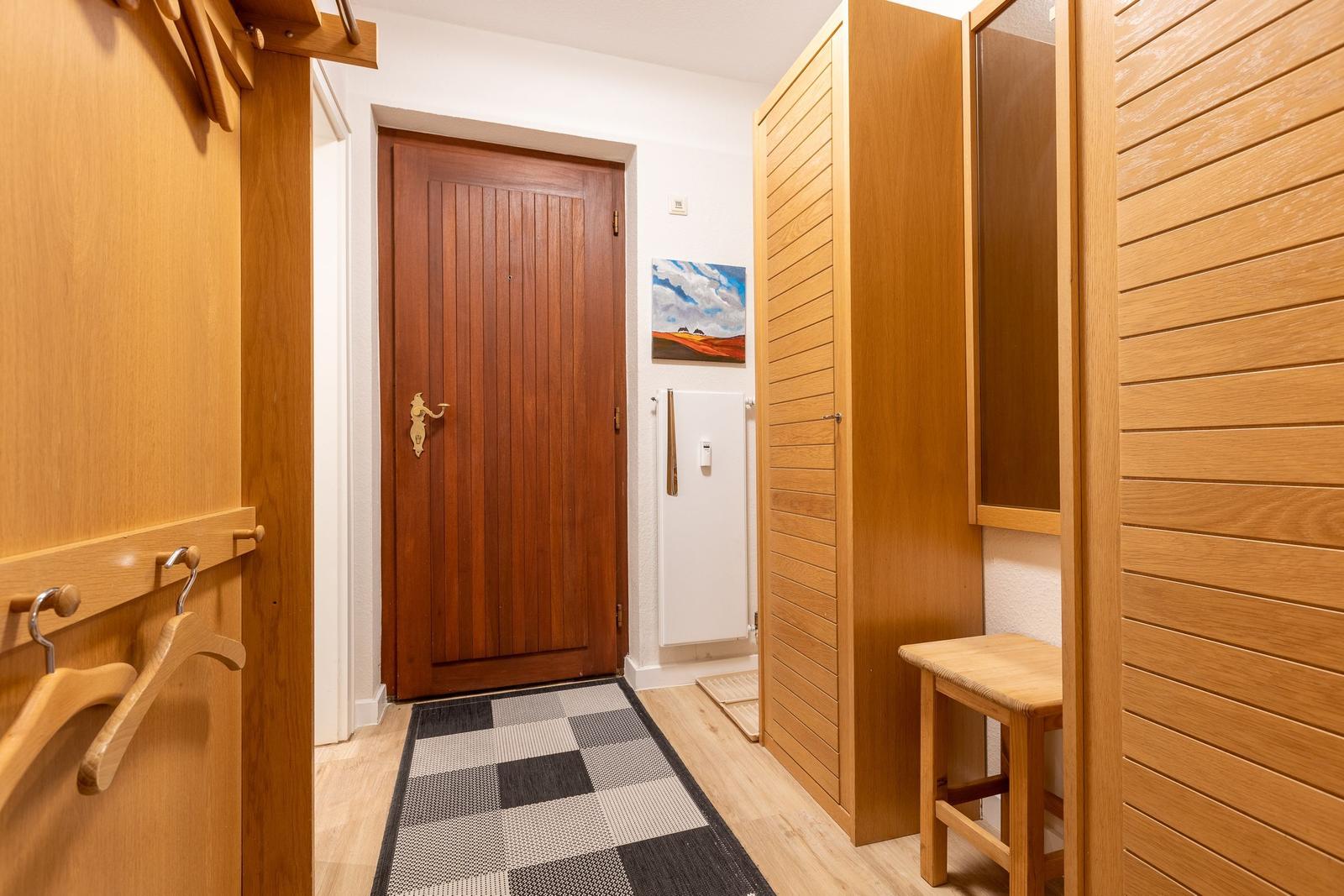 Entrance area with wooden doors, coat hooks, and tiled floor.
