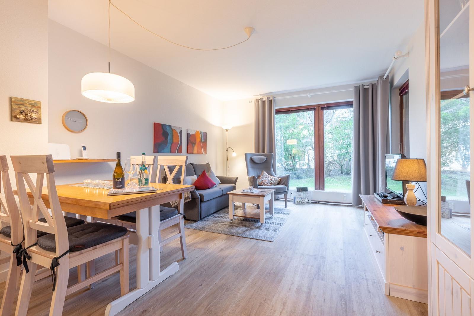 Living and dining area with wooden floor, sofa, dining table, and garden view.