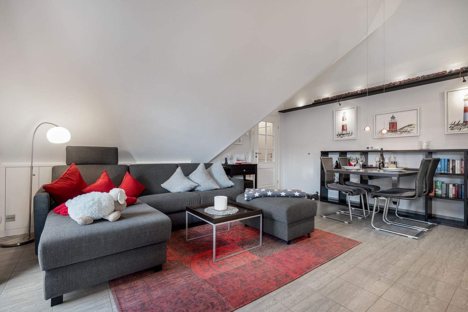 Wohn- und Essbereich mit Sofa, Tisch und Stühlen unter Dachschrägen.