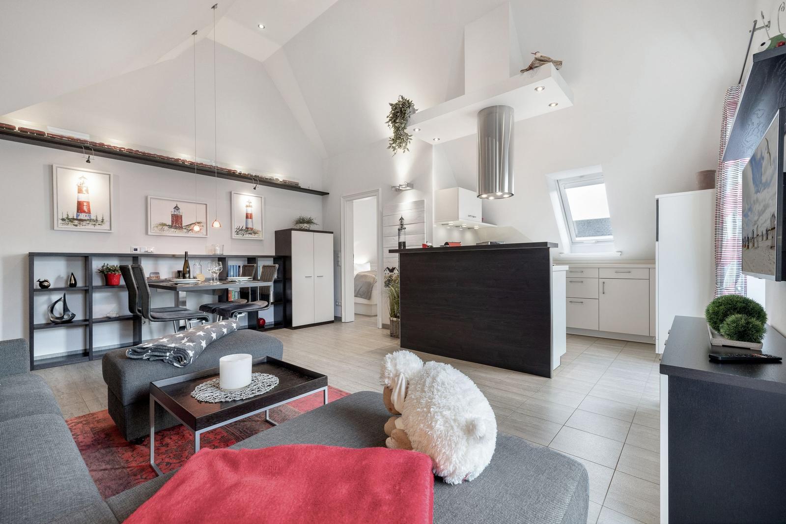 Wohn- und Küchenbereich mit Dachschrägen, Esstisch, Sofa und Fernseher.