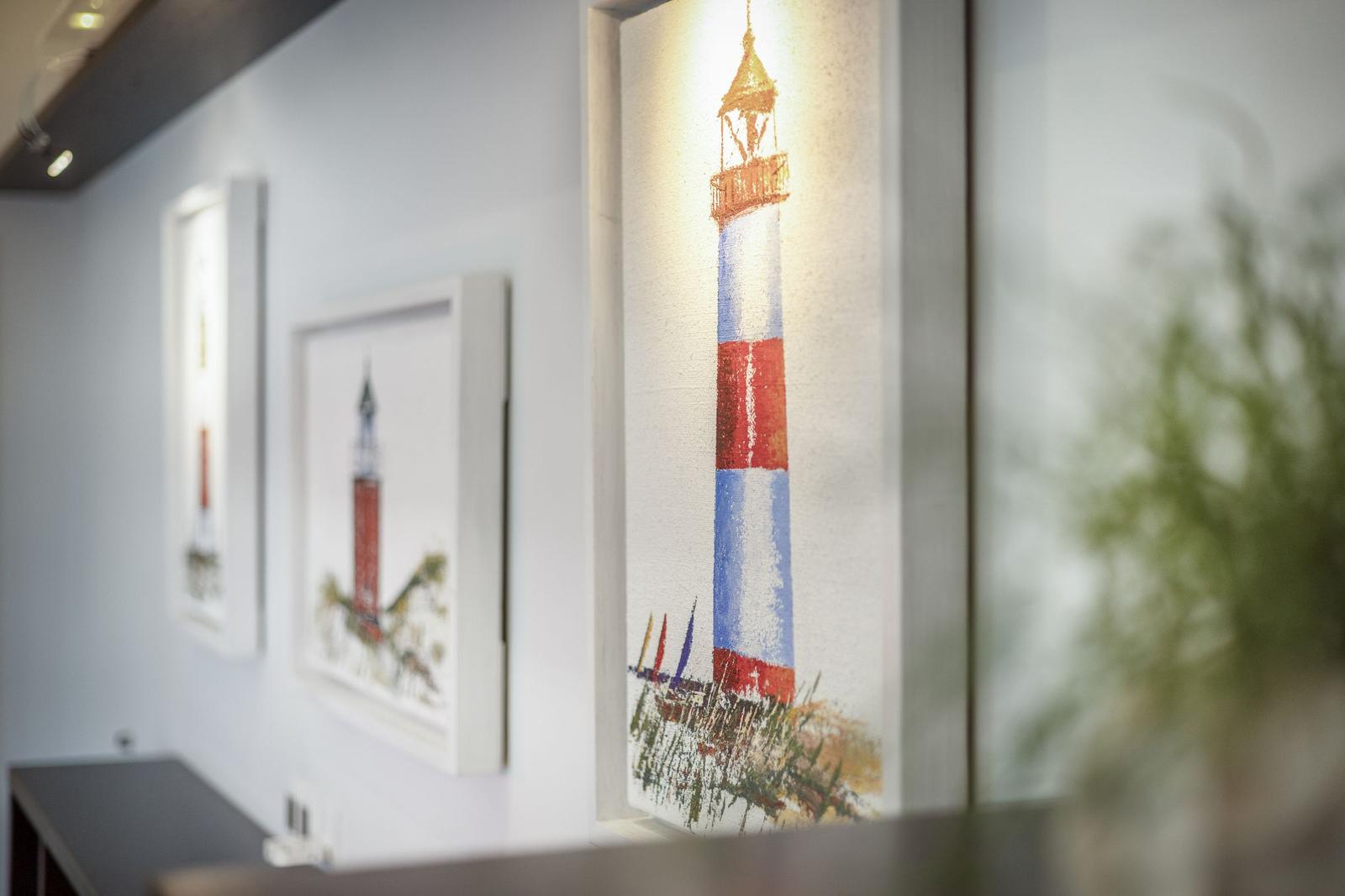Wand mit drei gerahmten Leuchtturm-Bildern in einem Flur.
