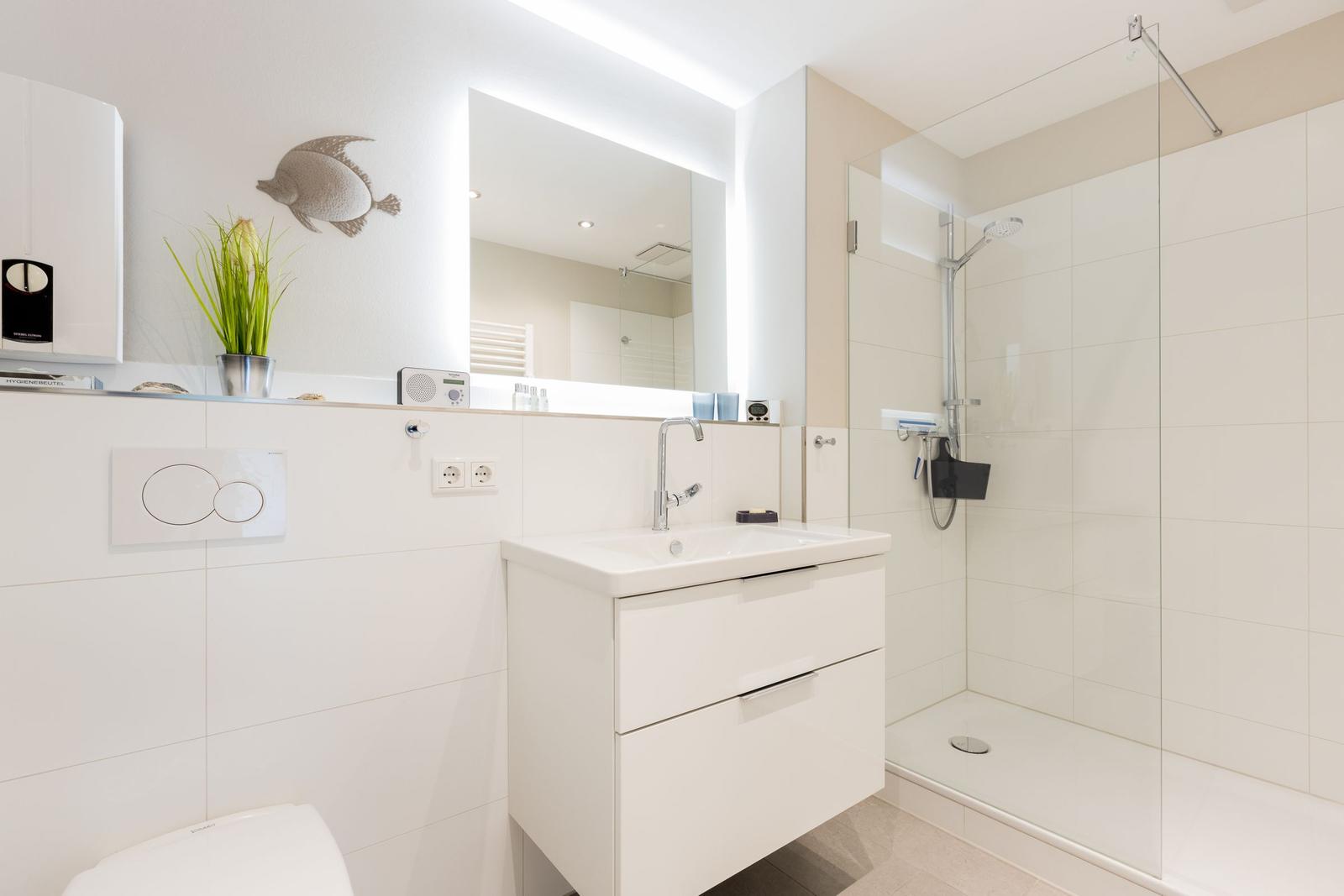 Badezimmer mit Dusche, Waschbecken und Spiegel