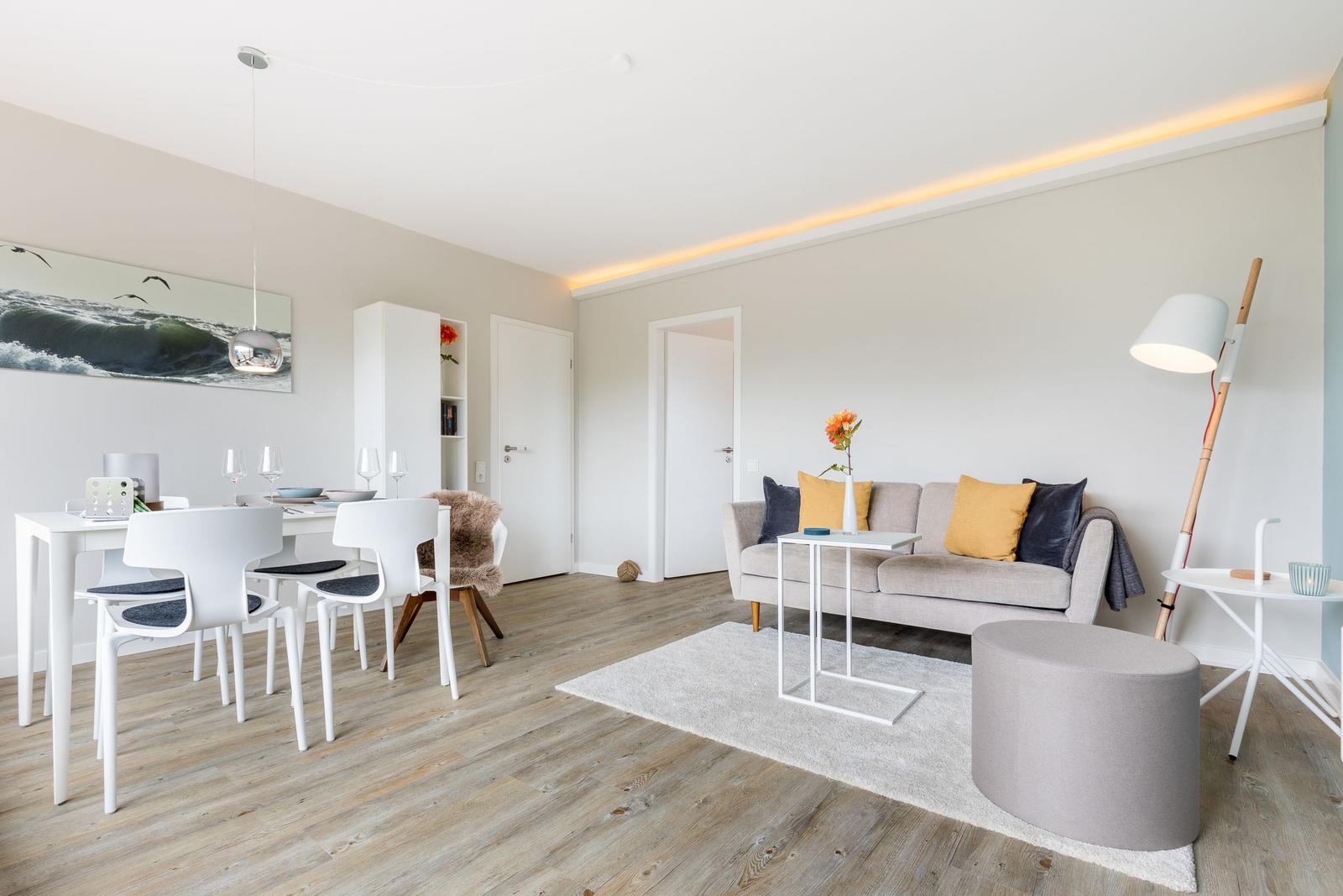 Wohn- und Essbereich mit Sofa, Tisch und Stühlen auf Holzboden.