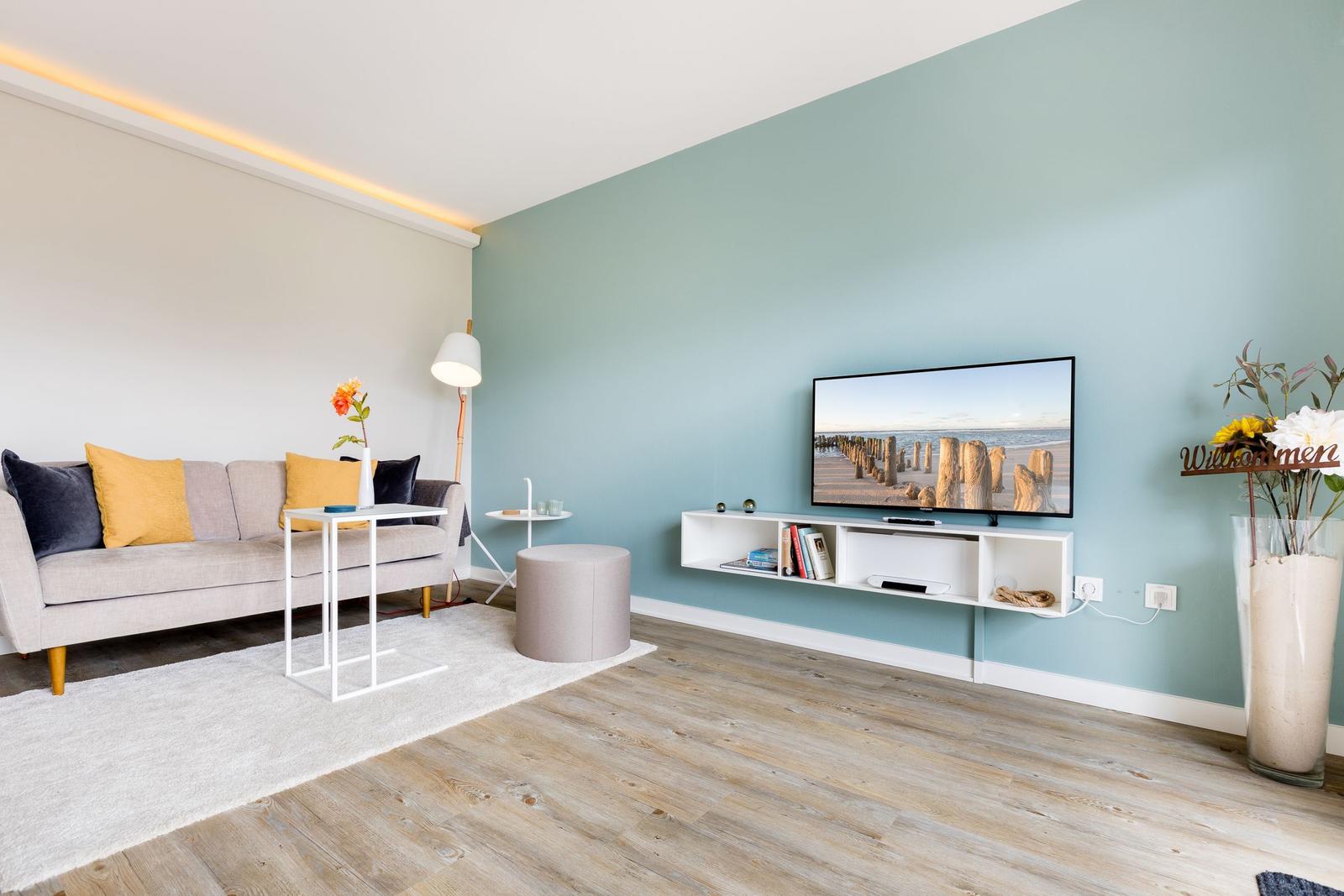 Wohnzimmer mit Sofa, Fernseher und Holzboden.