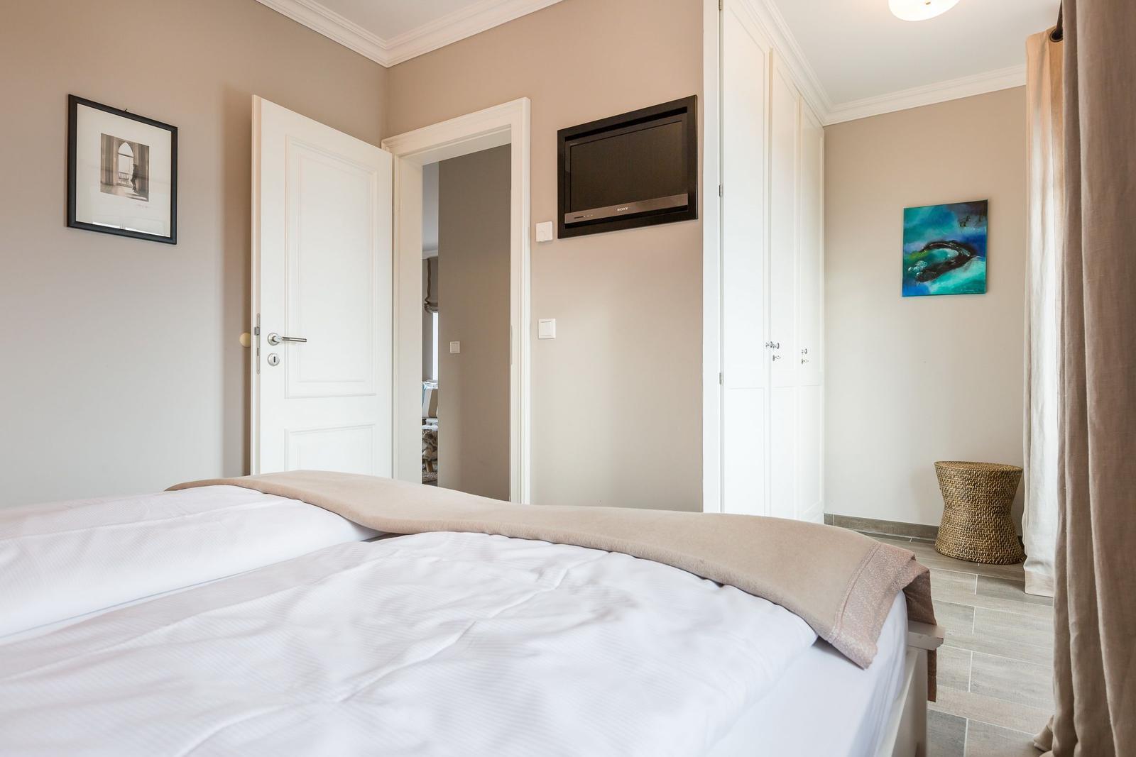 Schlafzimmer mit Bett, Fernseher und Kleiderschrank