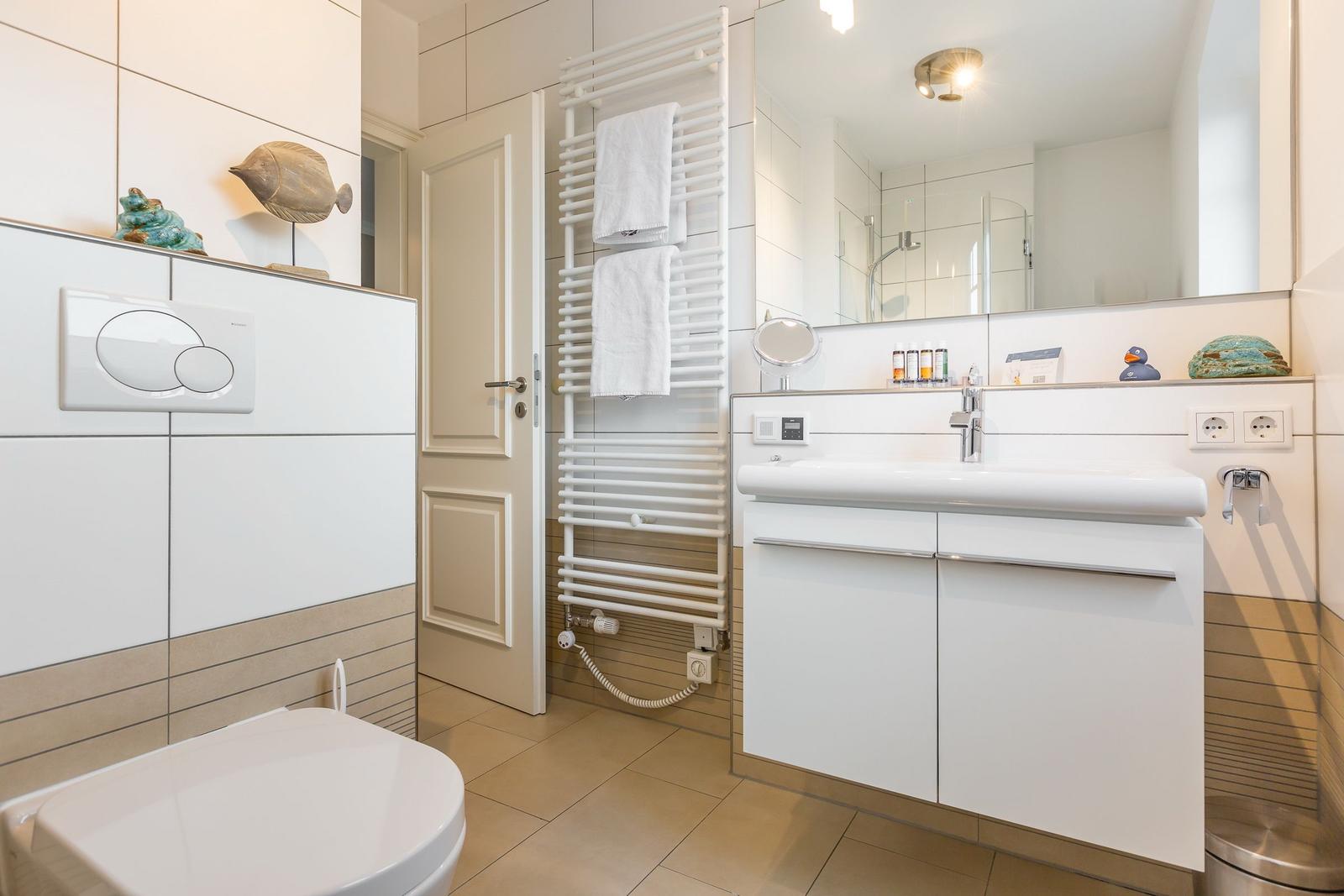 Badezimmer mit Waschbecken, Spiegel, Toilette und Handtuchheizung.