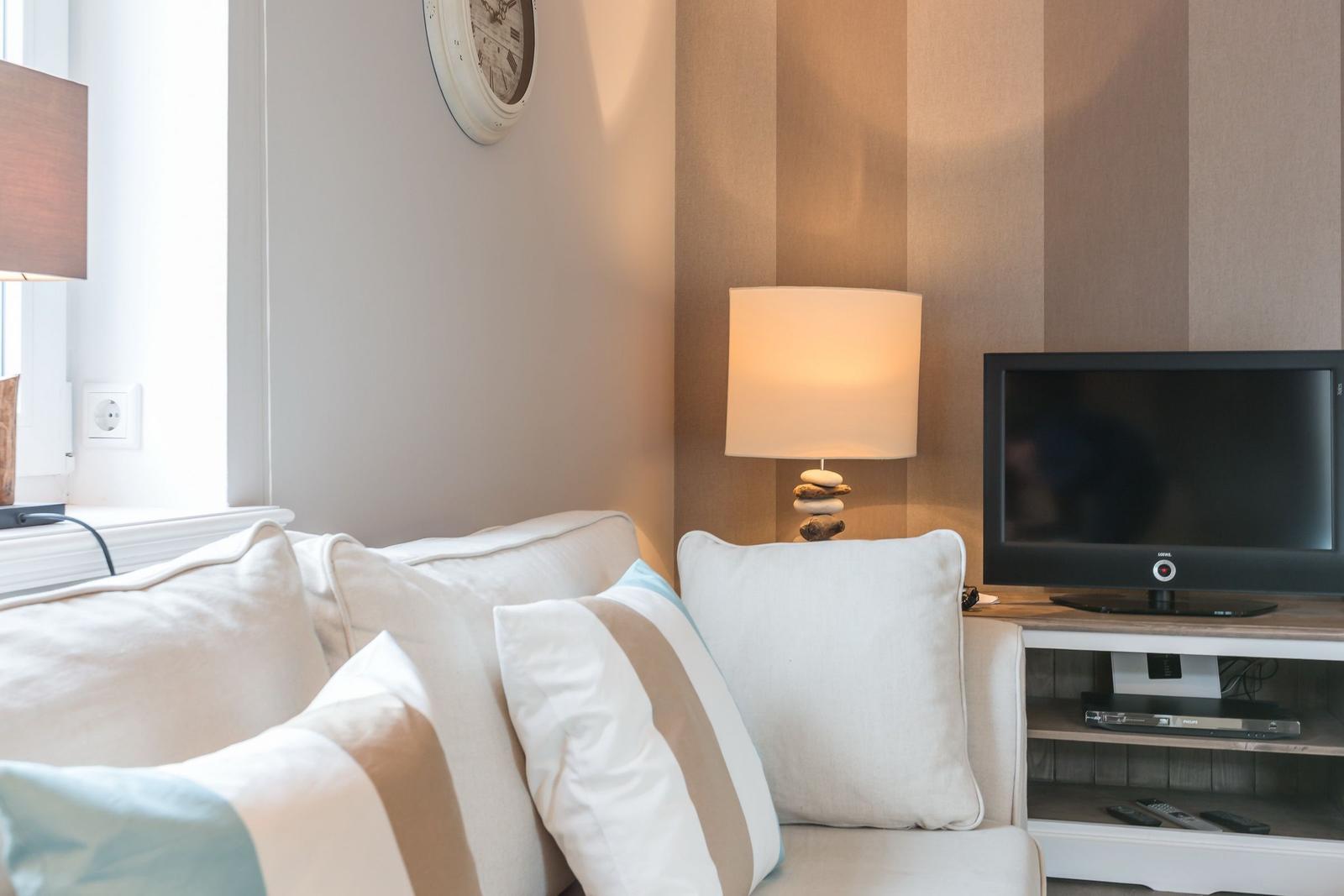 Ein Wohnbereich mit Sofa, Fernseher und Stehlampe.