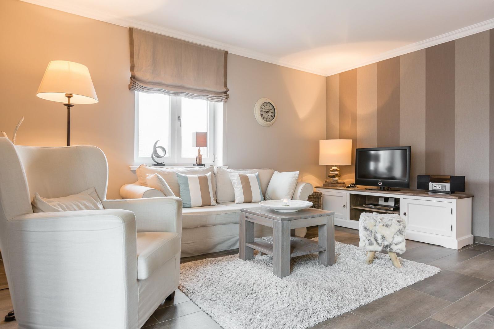 Wohnzimmer mit Sofa, Sessel, Couchtisch und Fernseher.