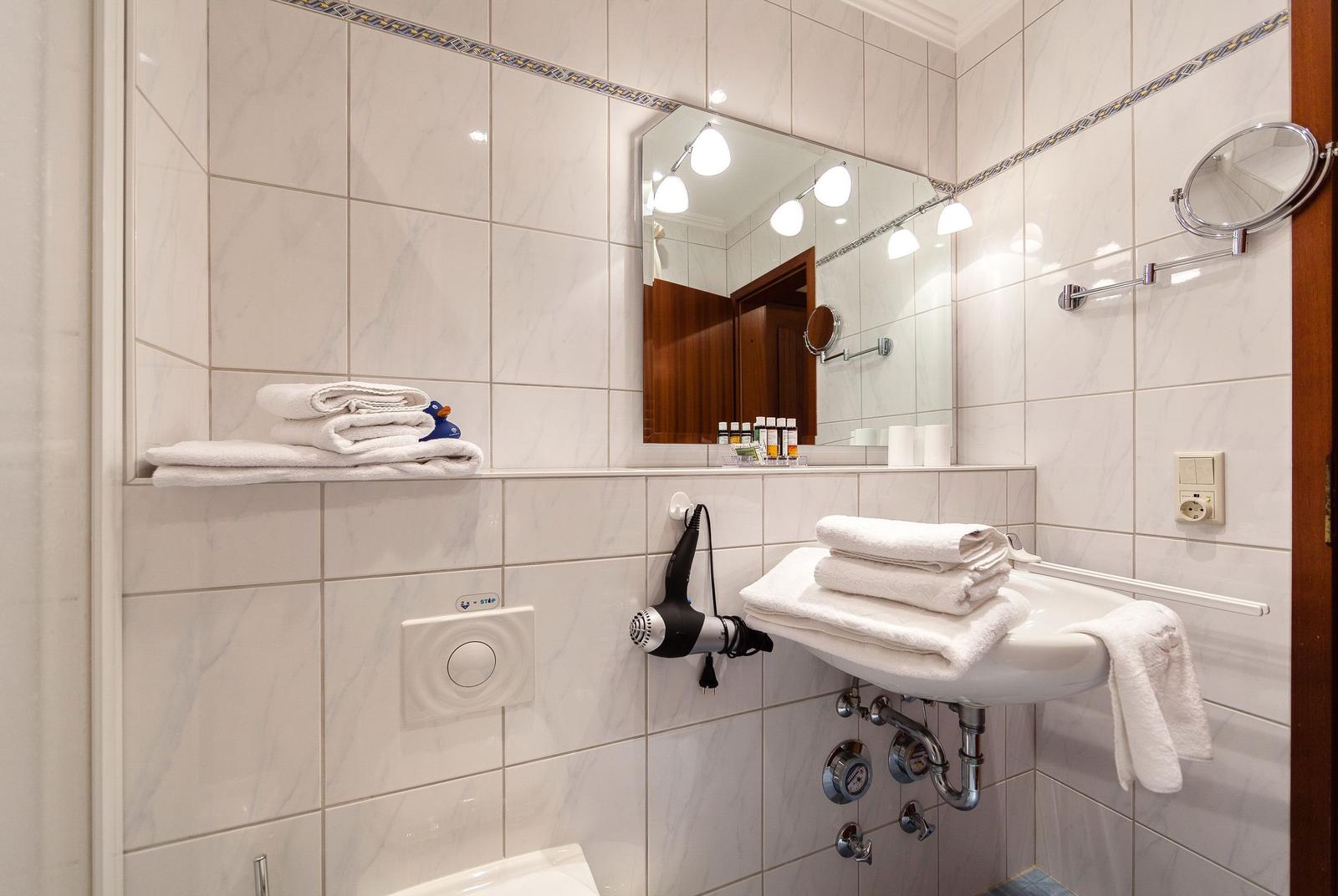 Badezimmer mit Spiegel, Handtuchhalter und Duschbereich.