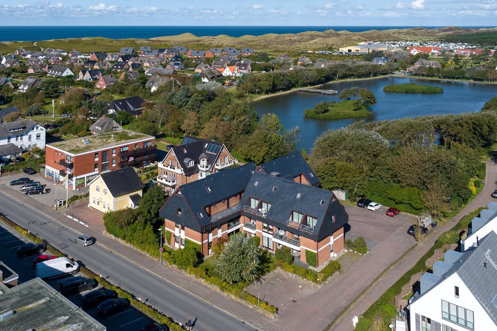 Haus mit Terrasse, See und Strand im Hintergrund