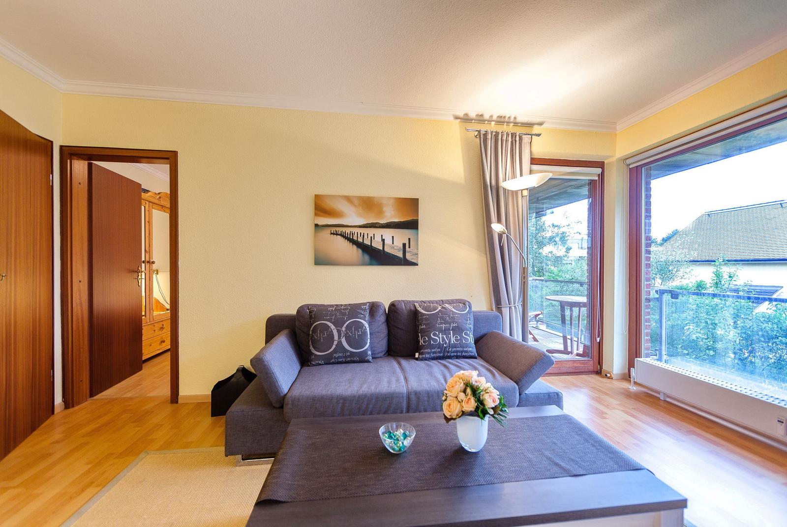 Wohnzimmer mit Sofa, Tisch und Blick auf Balkon
