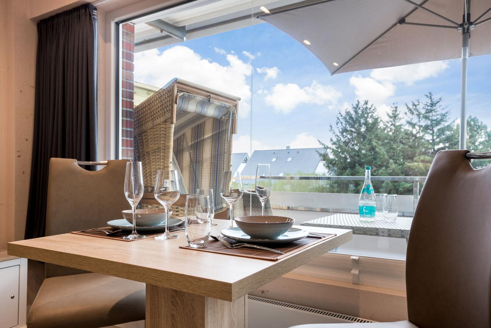 Dining table for four with view to terrace and sunshade.