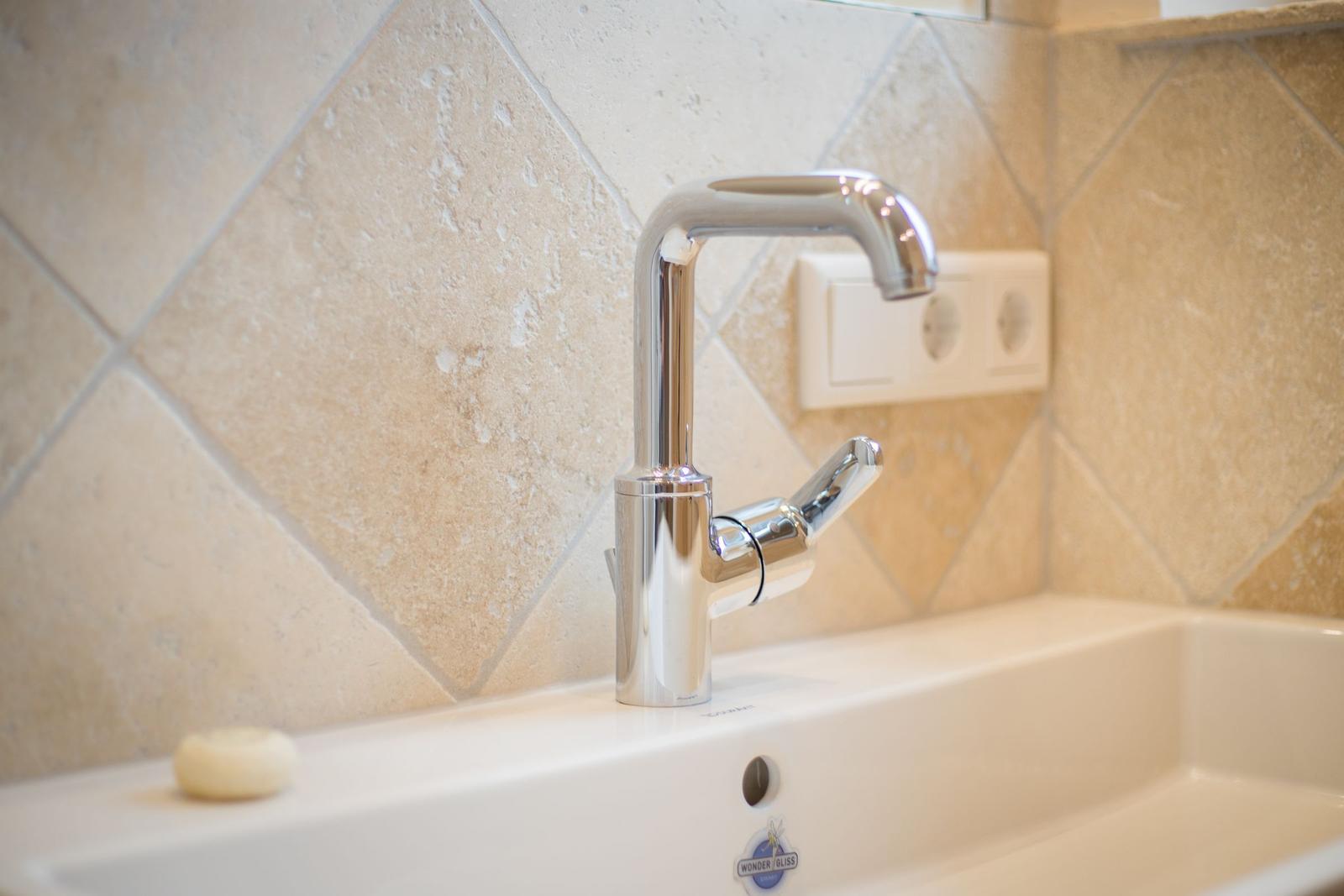 Sink with modern faucet and stone tile wall