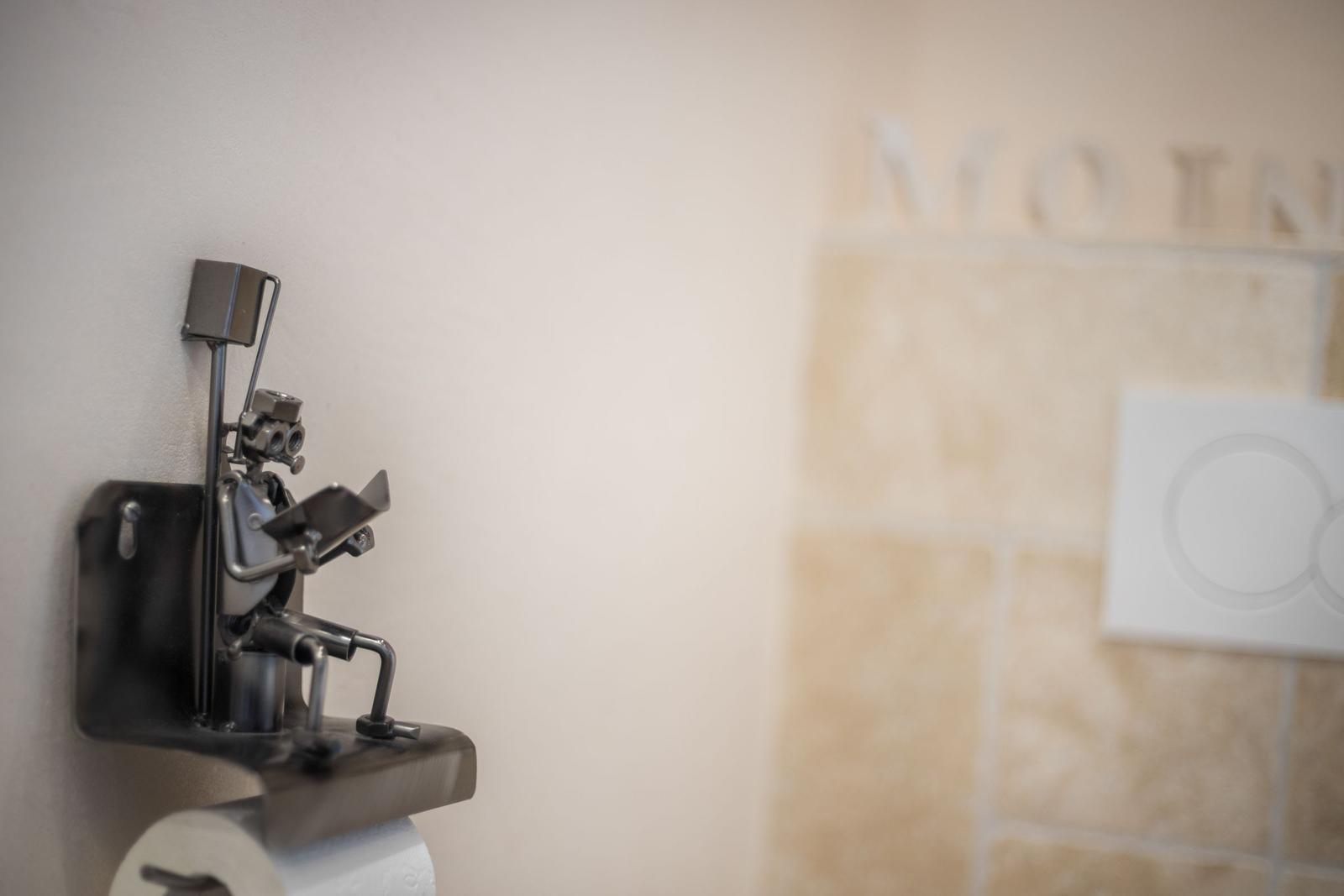 Toilet paper holder with metal figure on wall