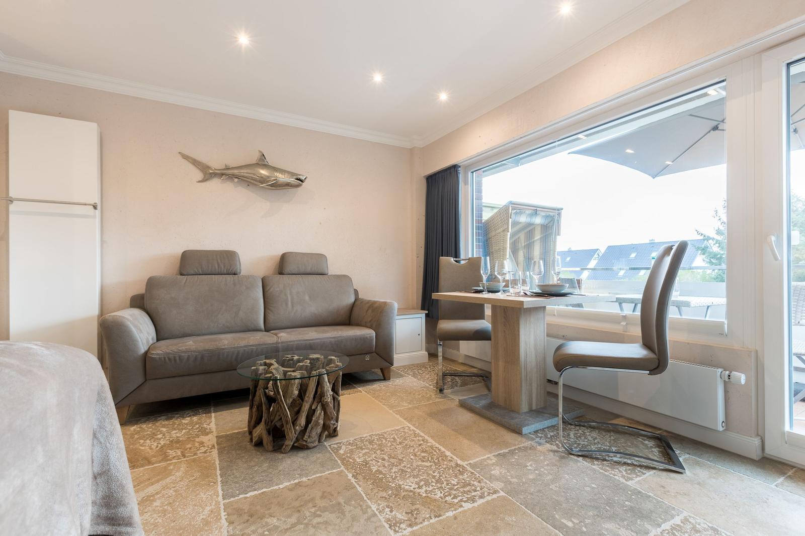 Living and dining area with sofa, table, and view of balcony.