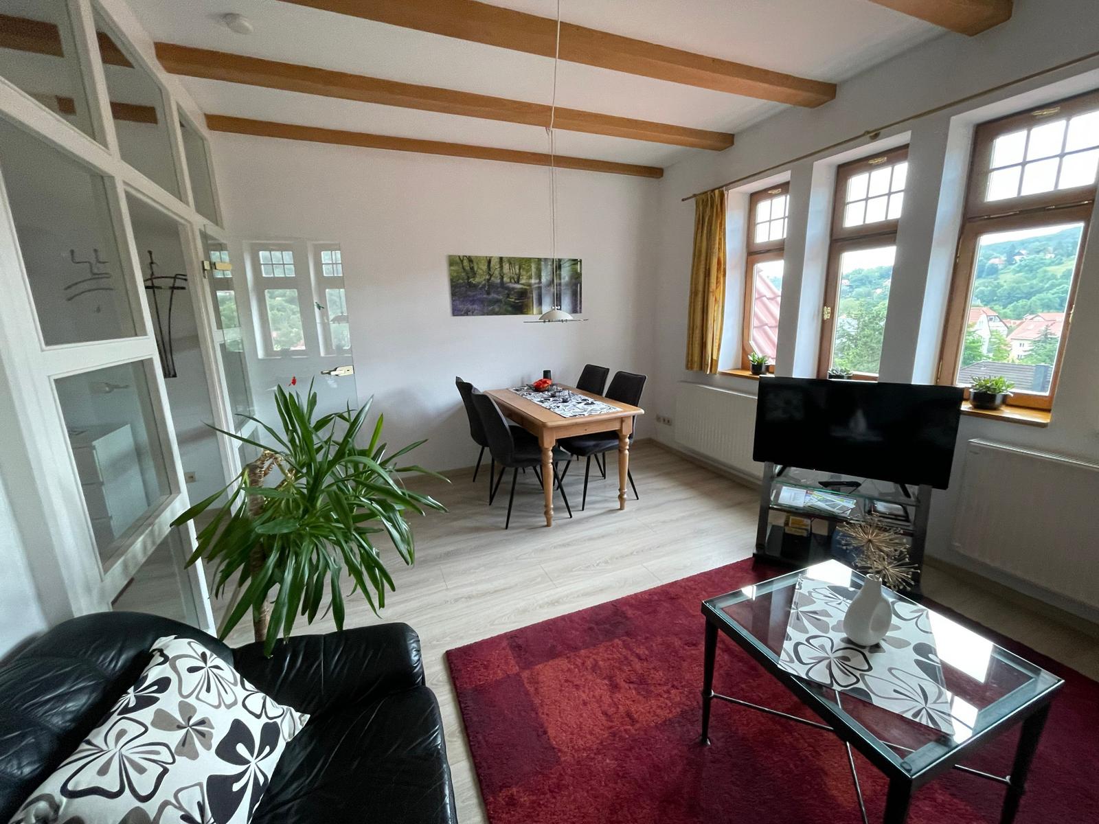 Wohnraum mit moderner Essecke, Flachbildschirm und gemütlicher Sitzecke.