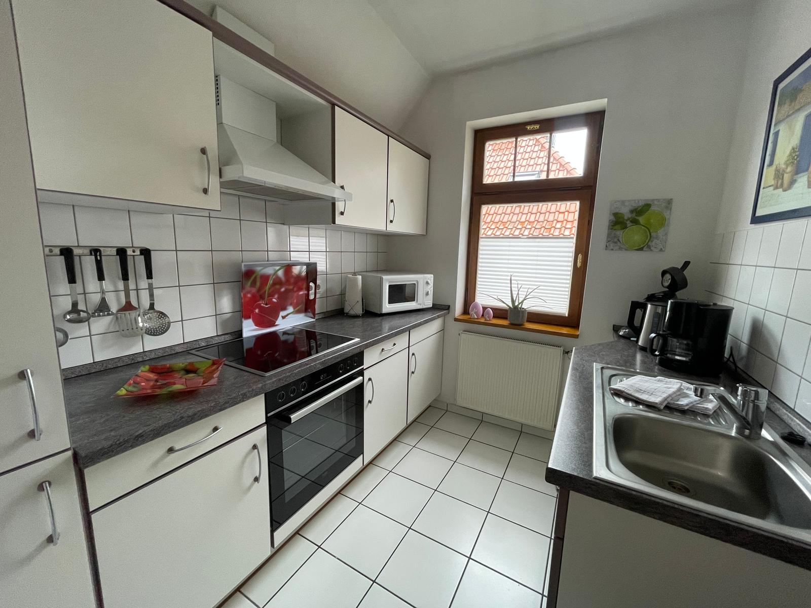 Küche mit hochwertigem Cerankochfeld, Backofen, Geschirrspüler, Kühl-Gefrierschrank, Mikrowelle, Kaffeemaschine, Wasserkocher und Toaster.