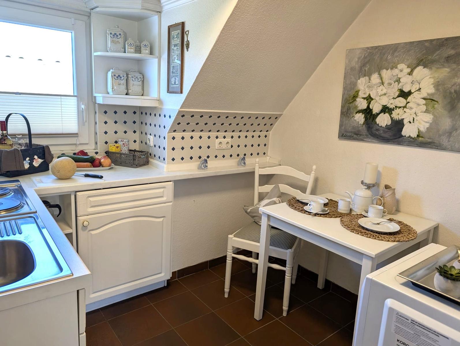 Küche mit Esstisch, Wandbild und Schränken