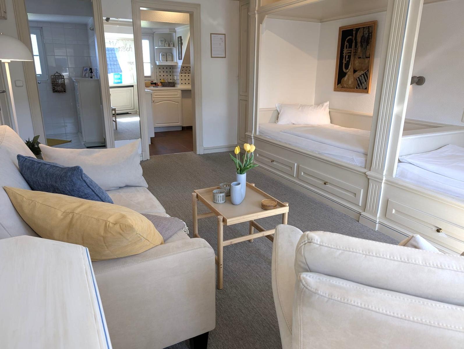 Wohnzimmer mit Sofa, Couchtisch und Blick auf Schlafzimmer mit zwei Betten.