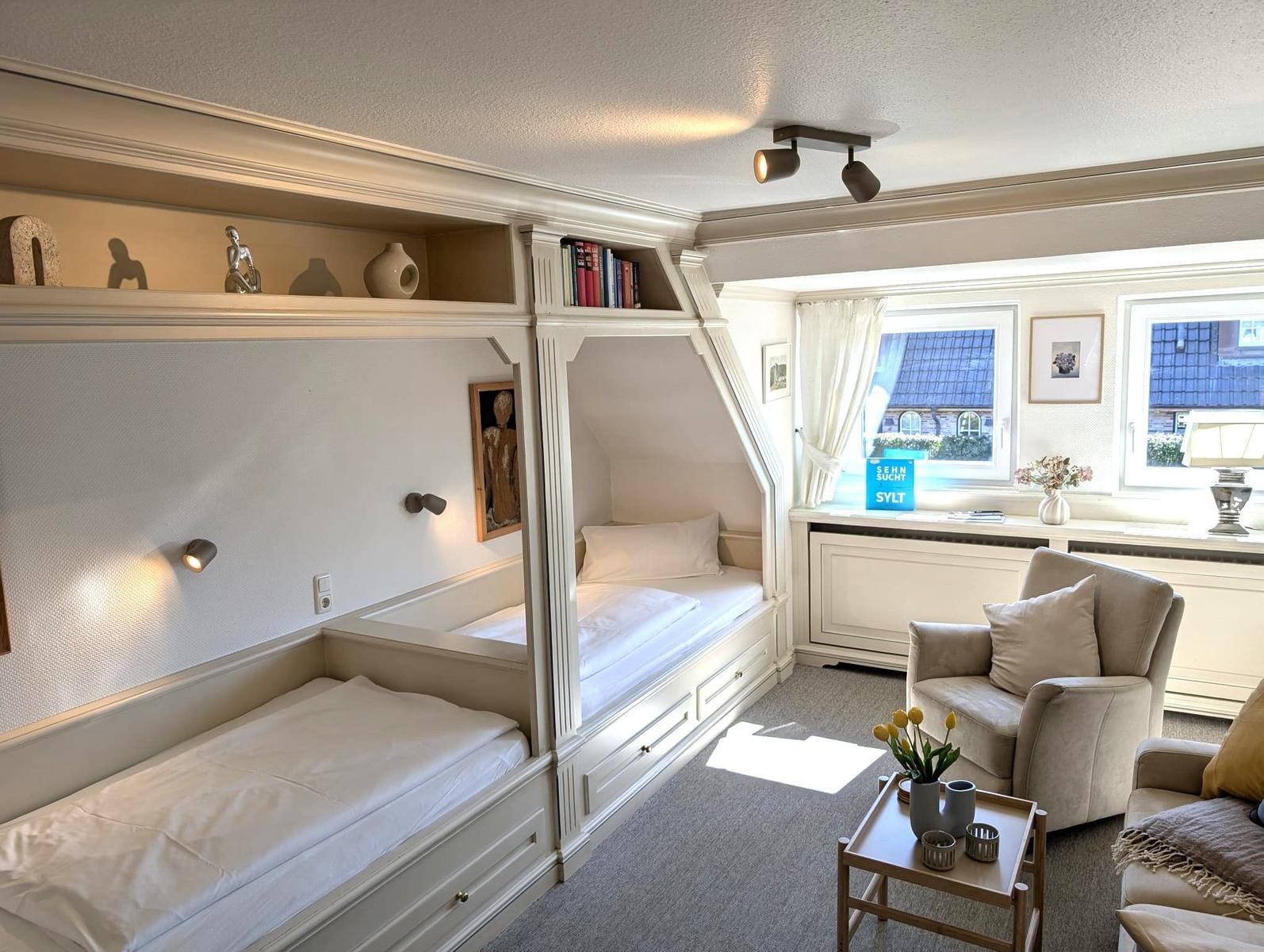 Zimmer mit zwei Betten, Sitzgelegenheit und Fensterblick.