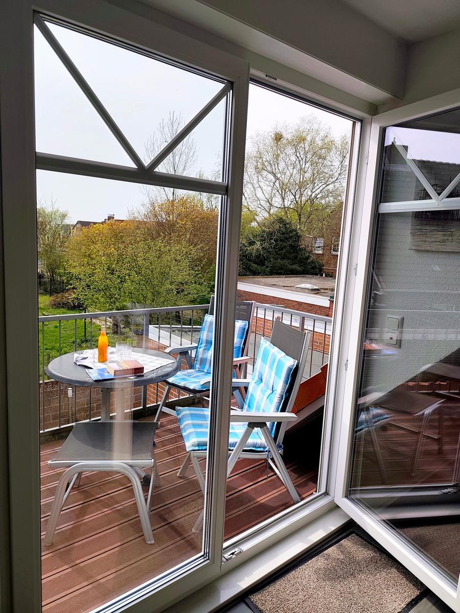 Terrasse mit Tisch, Stühlen und Blick auf Grünflächen.