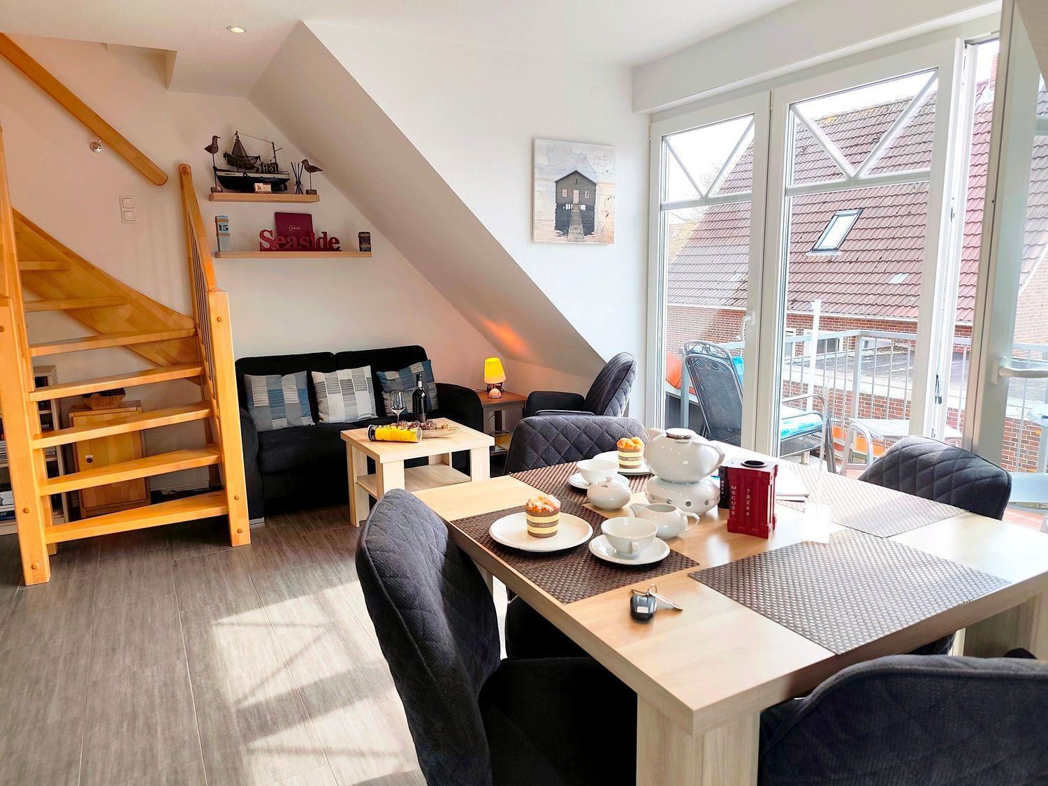 Wohn- und Essbereich mit Treppe, Sofa und Terrasse. Esstisch mit Platz für vier.