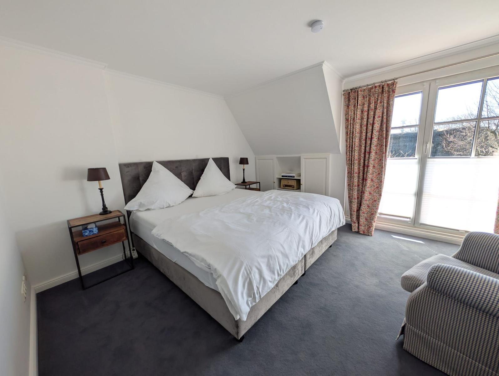 Bedroom with double bed, closet, and window with curtains.