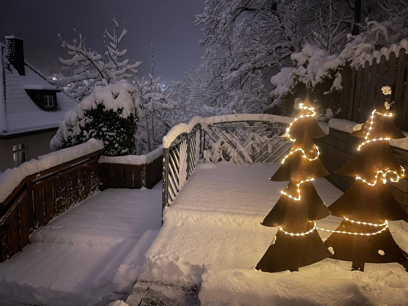 Die Terrasse liegt still und verschneit in der Winterlandschaft.