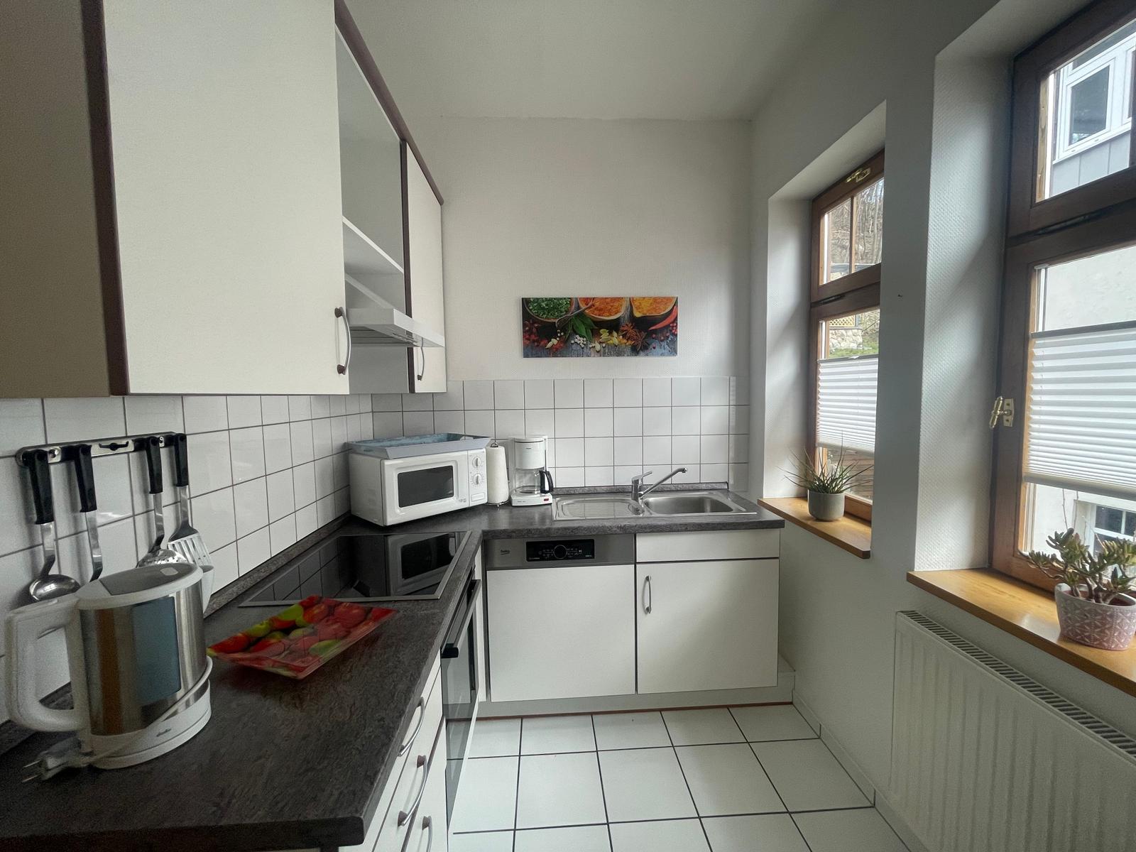 Küche mit hochwertigem Cerankochfeld, Backofen, Geschirrspüler, Kühl-Gefrierschrank, Mikrowelle, Kaffeemaschine, Wasserkocher und Toaster.