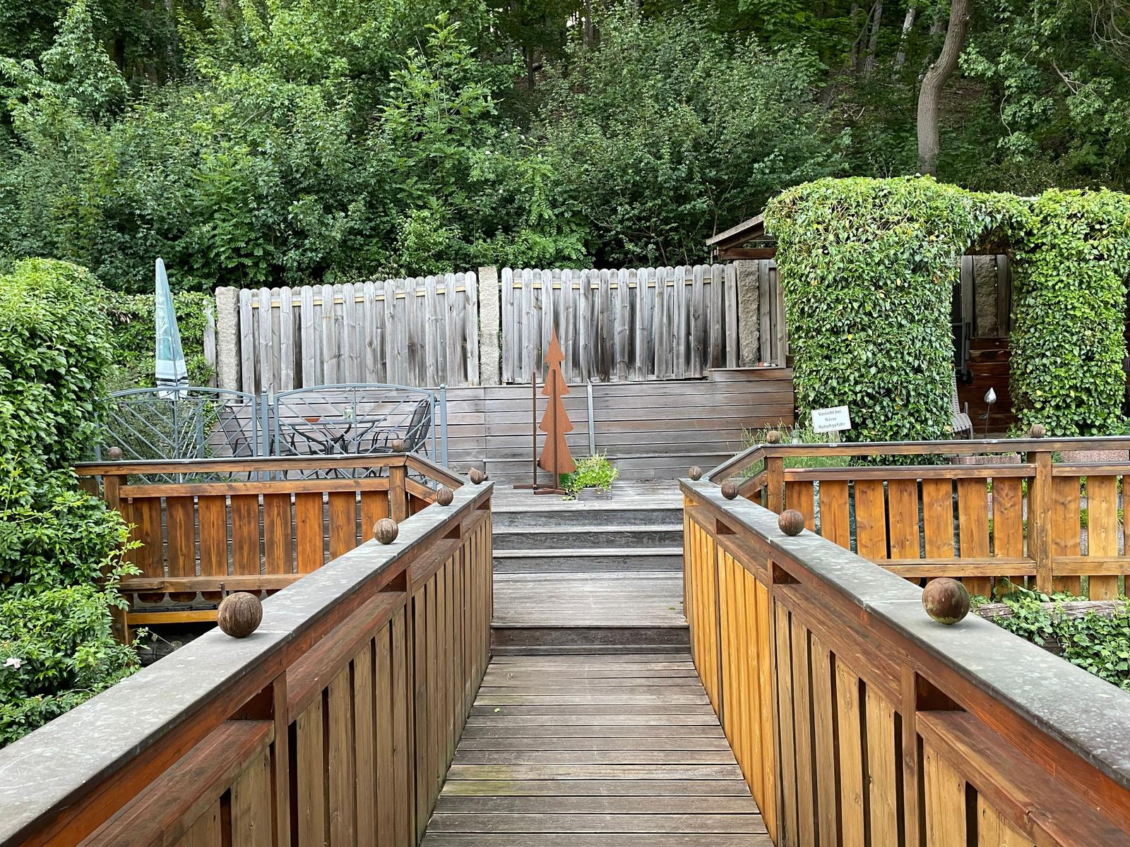 Über eine kleine Brücke erreichen Sie die ruhig gelegene Terrasse direkt am Waldrand.