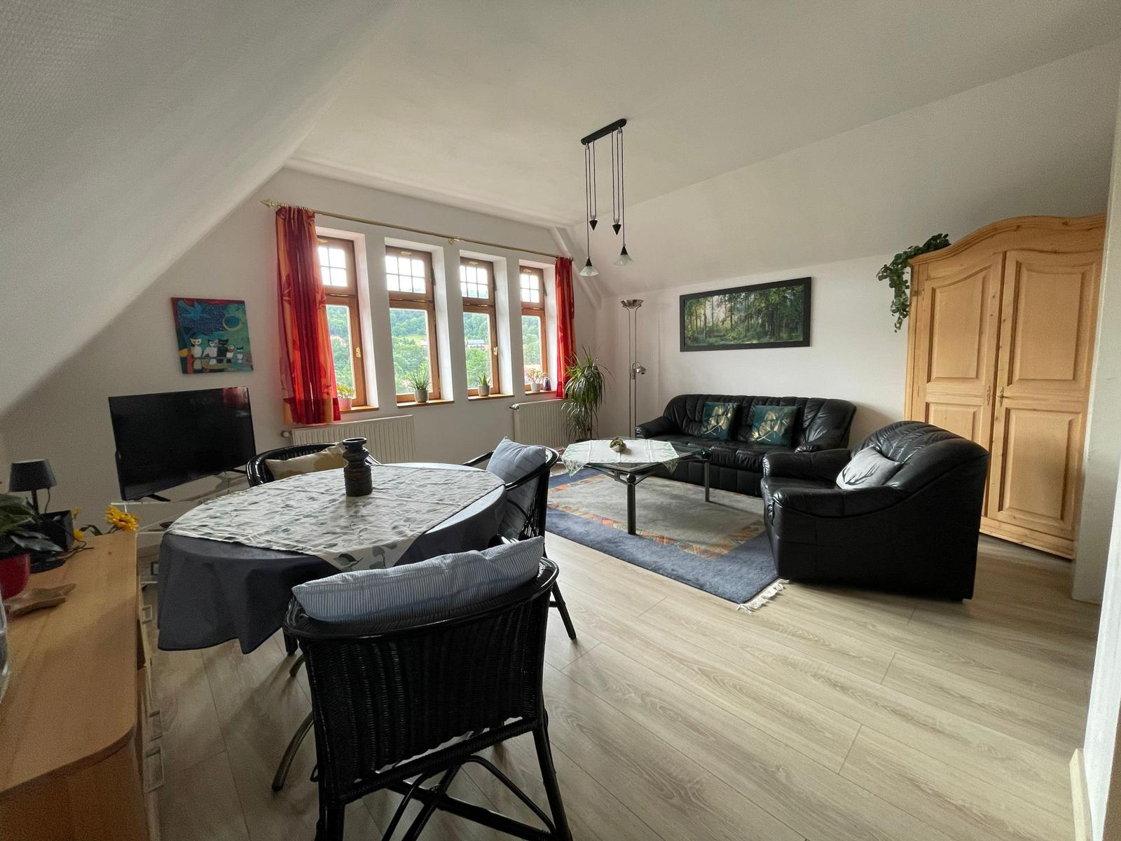 Wohnraum mit moderner Essecke, Flachbildschirm und gemütlicher Sitzecke.