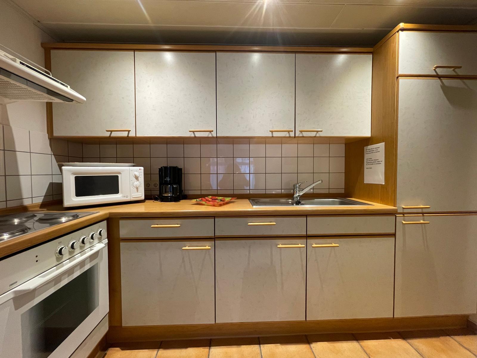 Küche mit 4-Platten-Herd, Backofen, Kühl-Gefrierschrank, Mikrowelle, Kaffeemaschine, Wasserkocher und Toaster.