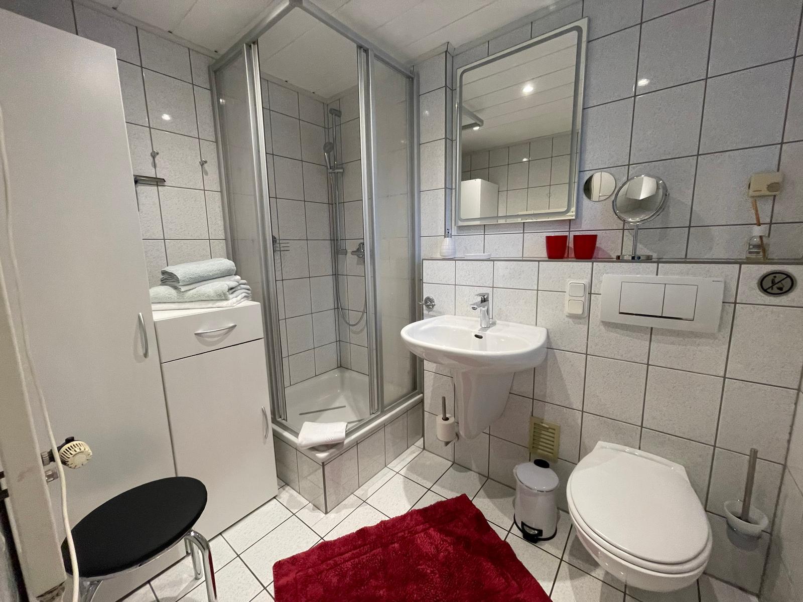 Bad mit Toilette, Dusche und Waschbecken mit beleuchtetem Spiegel.