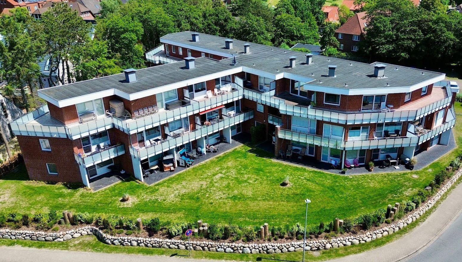 Moderne Mehrfamilienwohnung mit Balkonen und grünem Gartenbereich.