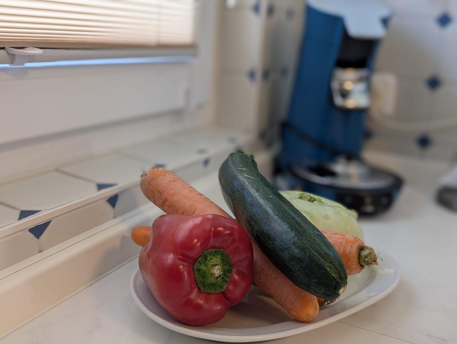 Auf dem Tisch liegen rote Paprika, Karotte, Zucchini und Käse.