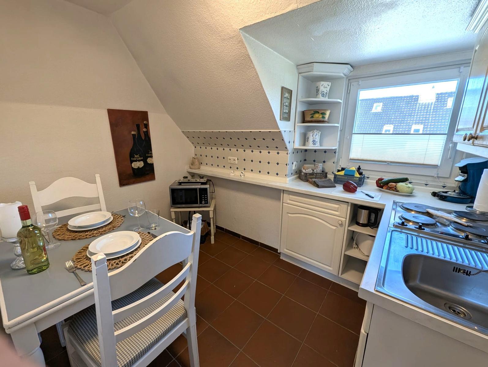Küche mit Essbereich, Fenster, Spüle und Kochfeld.