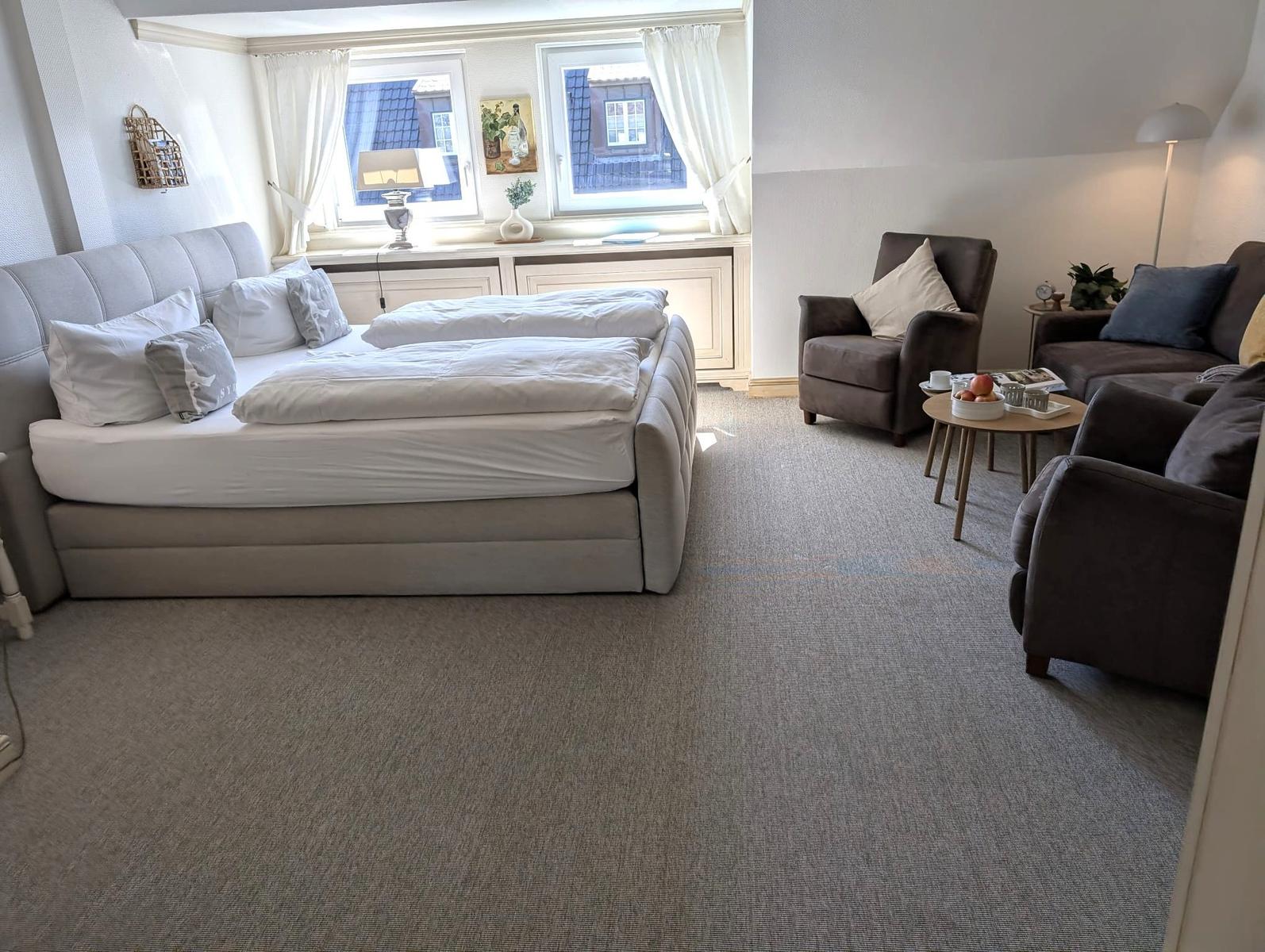 Schlafzimmer mit Doppelbett, Sitzbereich und Fenster