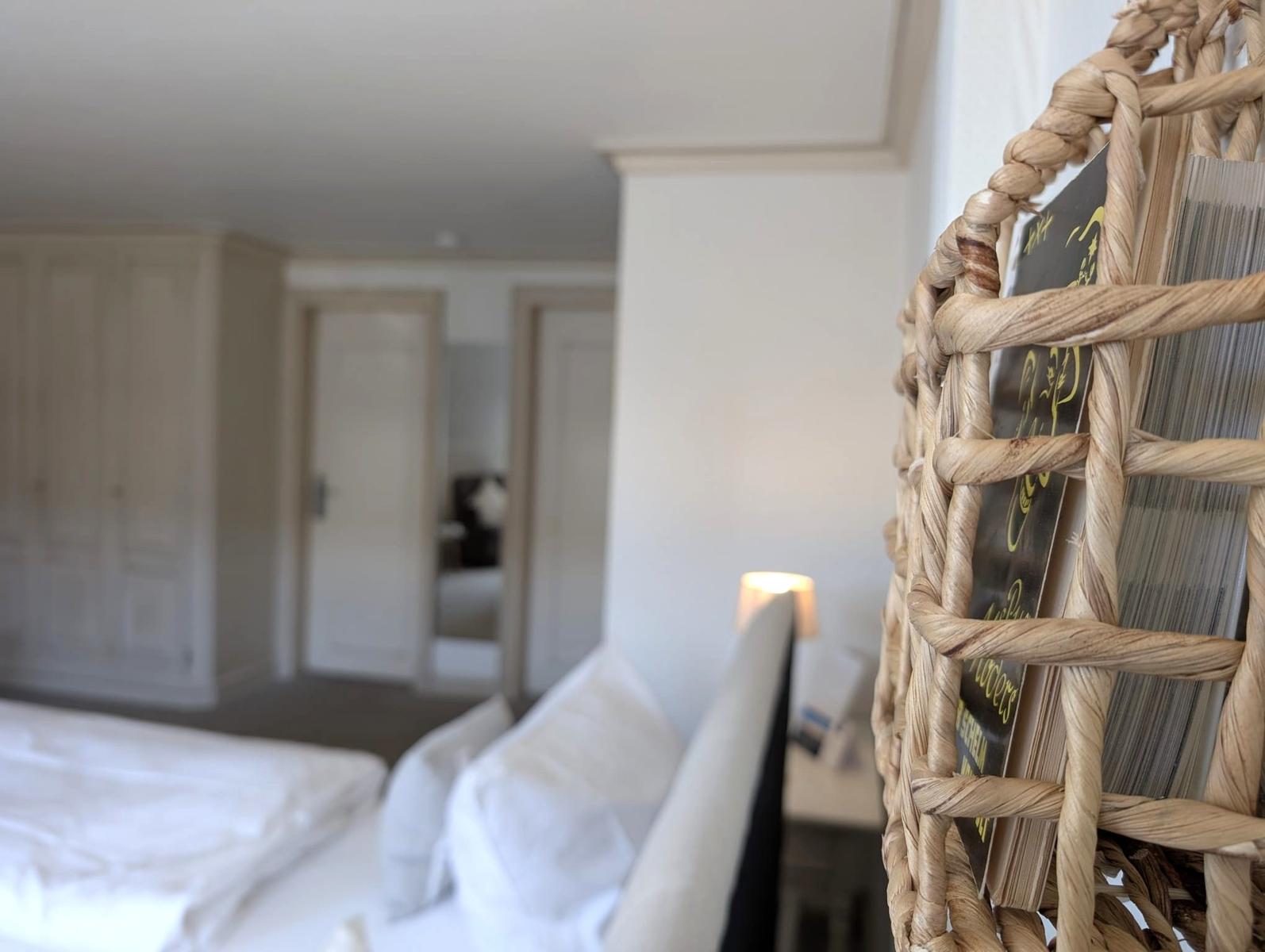 Schlafzimmer mit Bett, Nachttisch und geflochtenem Regal