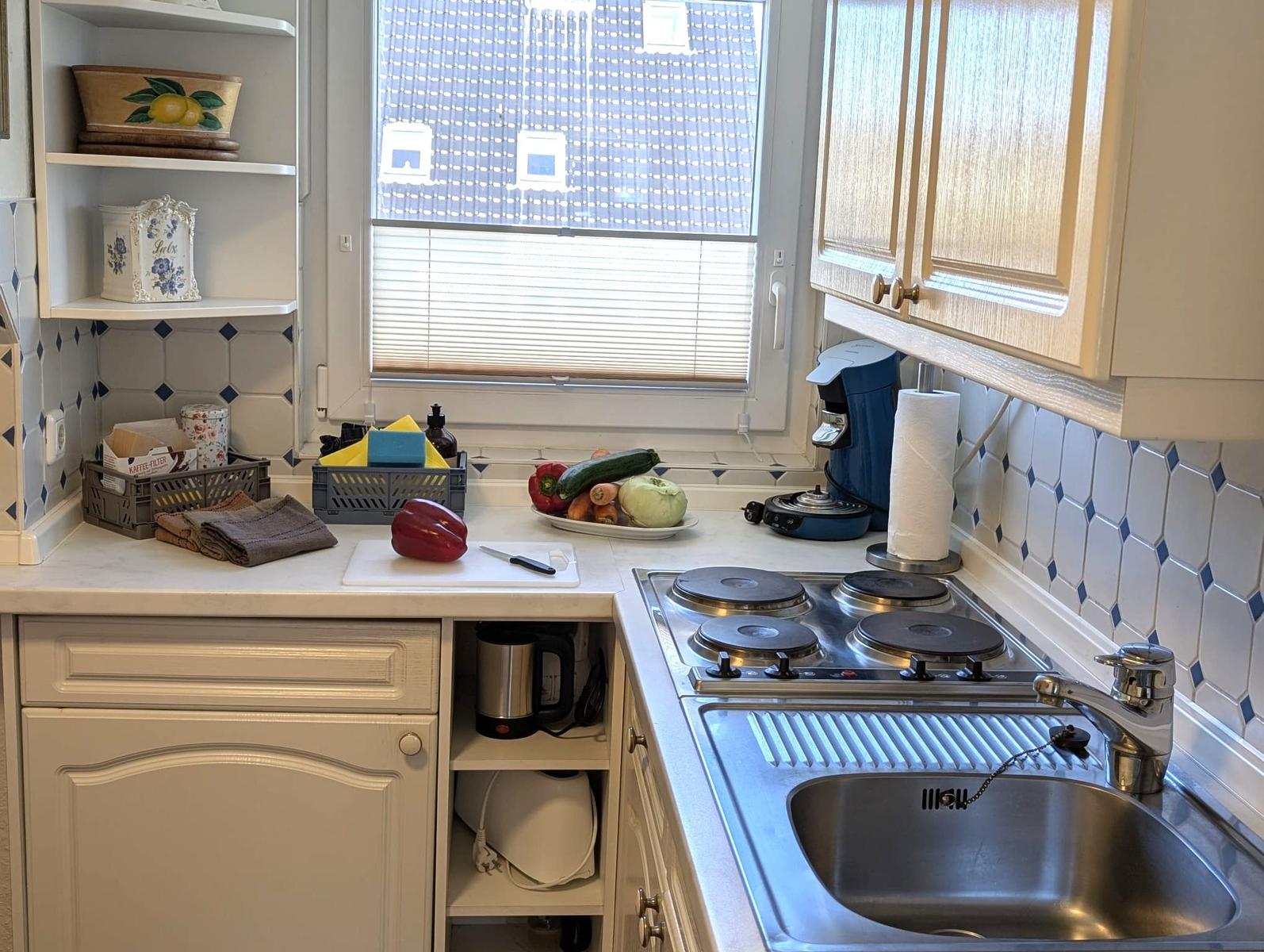 Küche mit Arbeitsplatte, Spüle, Herd und Fenster