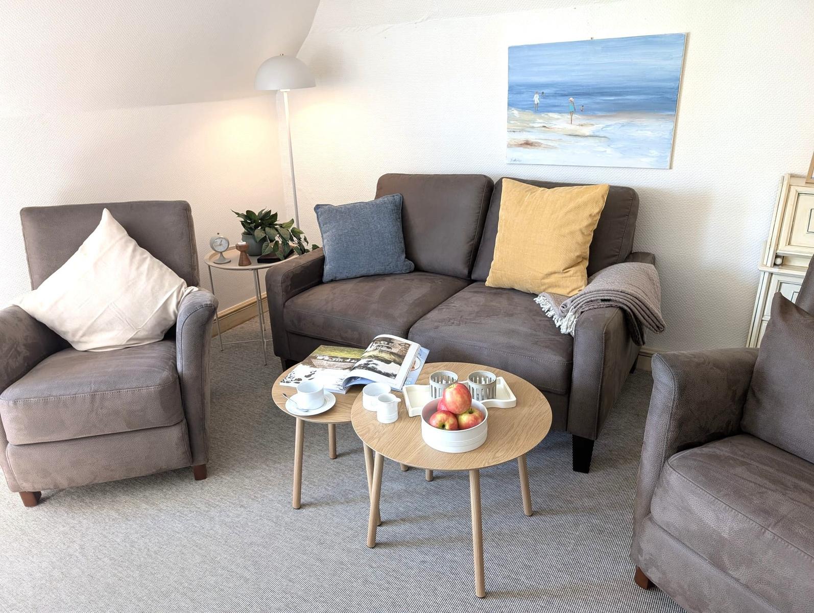 Ein Wohnzimmer mit Sofa, zwei Sesseln und einem runden Tisch.