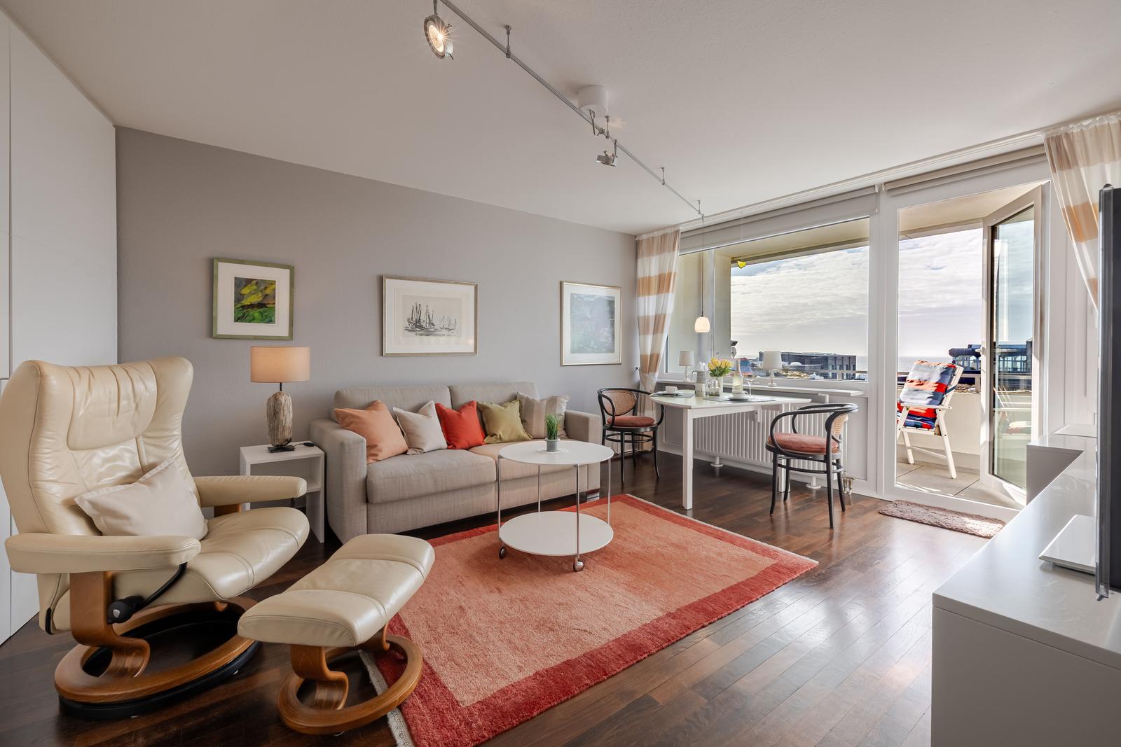 Wohnzimmer mit Sofa, Sessel und Terrasse mit Blick