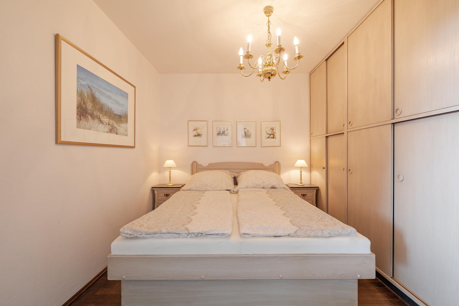 Schlafzimmer mit Doppelbett, Kleiderschrank und Kronleuchter.
