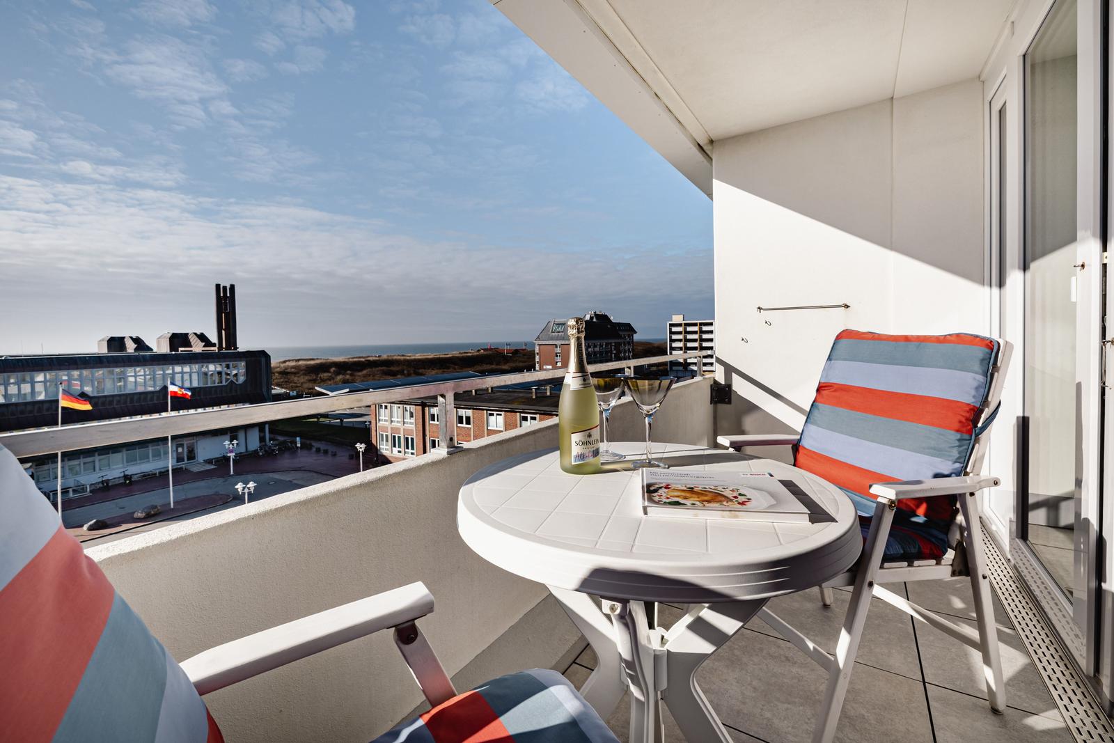 Balkon mit Tisch, Stühlen und Blick auf das Meer.