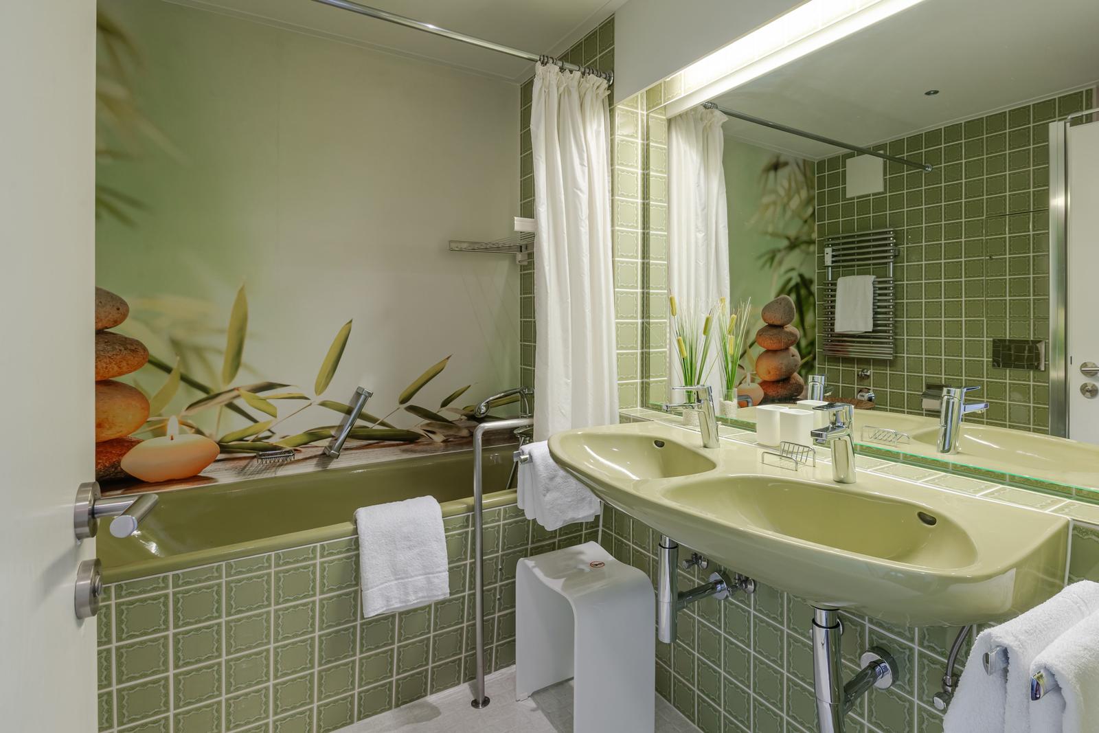 Bad mit Dusche, Waschbecken und Spiegel. Wandbild mit Steinen und Bambus.