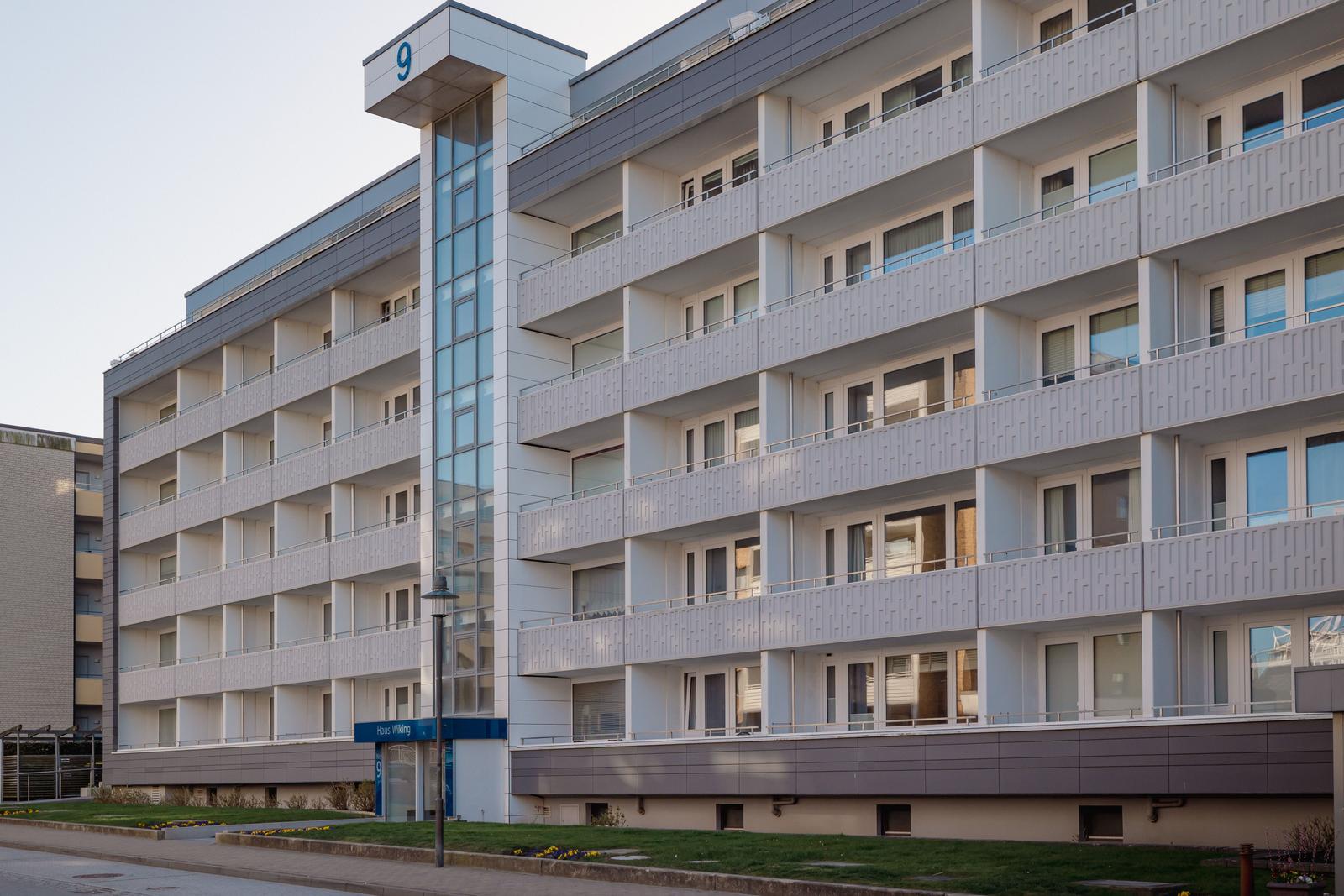 Modernes Mehrfamilienhaus mit Balkonen und Glasfassade. Hausnummer 9 sichtbar.