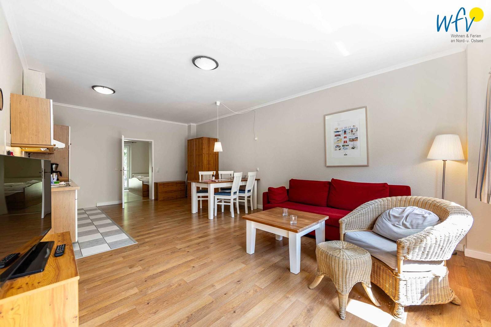 Wohnung mit Essbereich, rotem Sofa und Kamin. Holzboden und moderne Einrichtung.